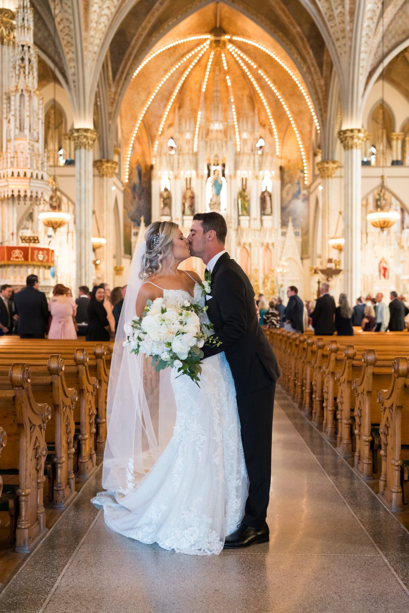 A bride and groom kiss in the center aisle of Detroit's Sweetest Heart of Mary Catholic Church on their wedding day.  