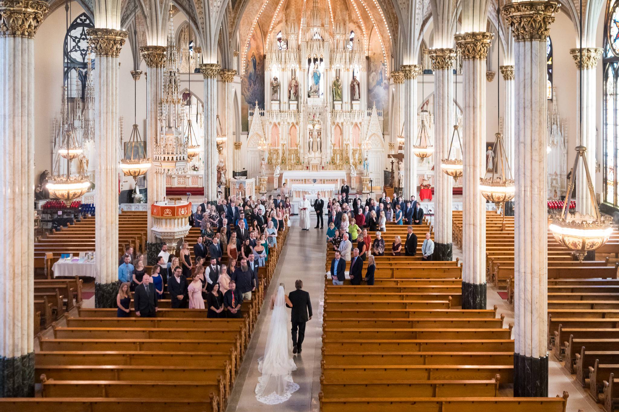 A balcony view of a bride walking down the aisle of her wedding at Detroit's Sweetest Heart of Mary Catholic Church.