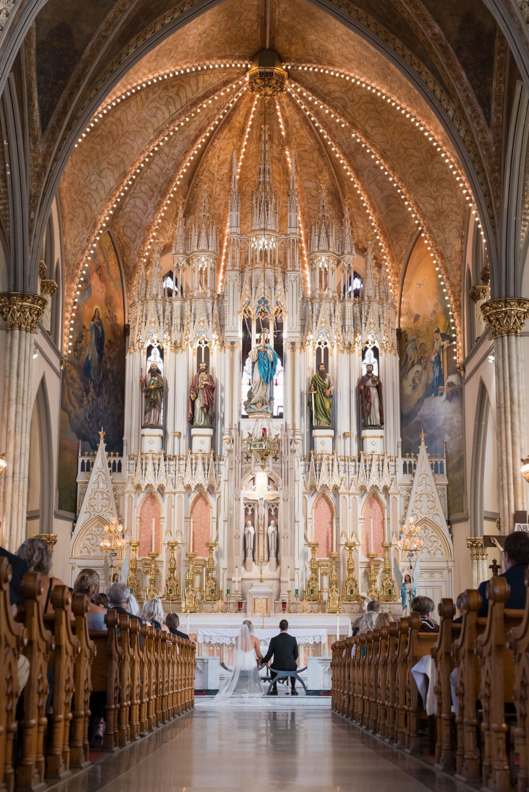 A bride and groom sit in front of the altar of Detroit's Sweetest Heart of Mary Catholic Church on their wedding day.  