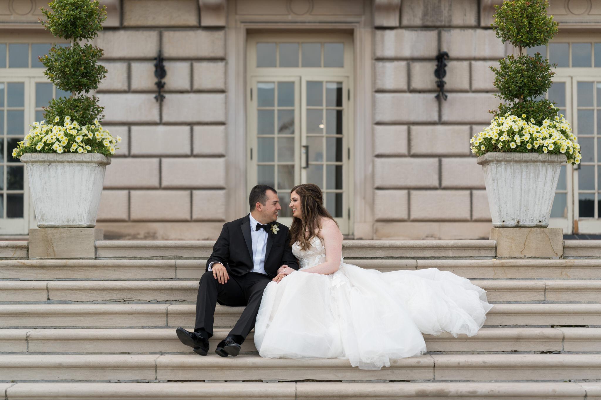A bride and groom sit on steps during their wedding at the War Memorial.  