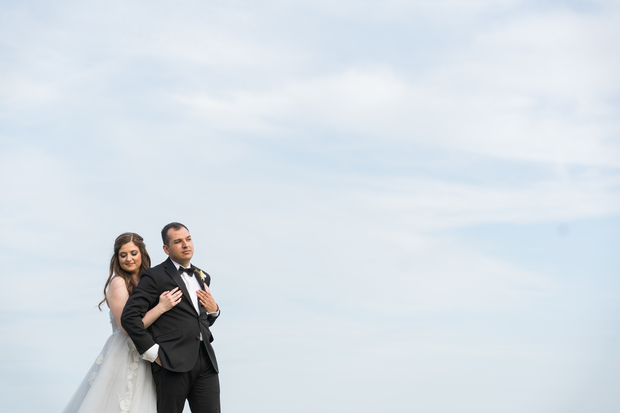 The bride and groom  are photographed against a blue sky during their wedding at The War Memorial.  