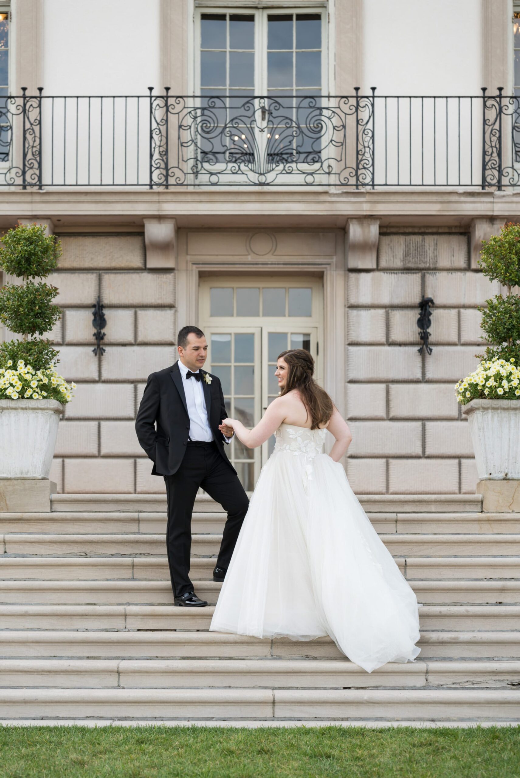 A bride and groom walk up steps during their wedding at the War Memorial.  