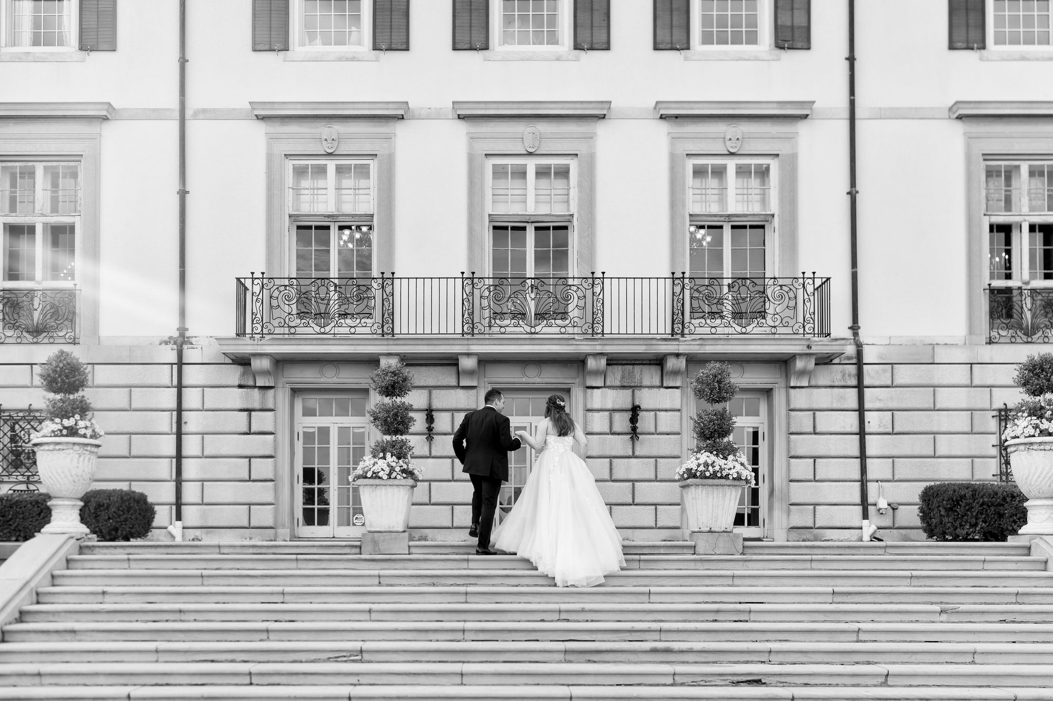 A bride and groom walk up steps during their wedding at the War Memorial.  