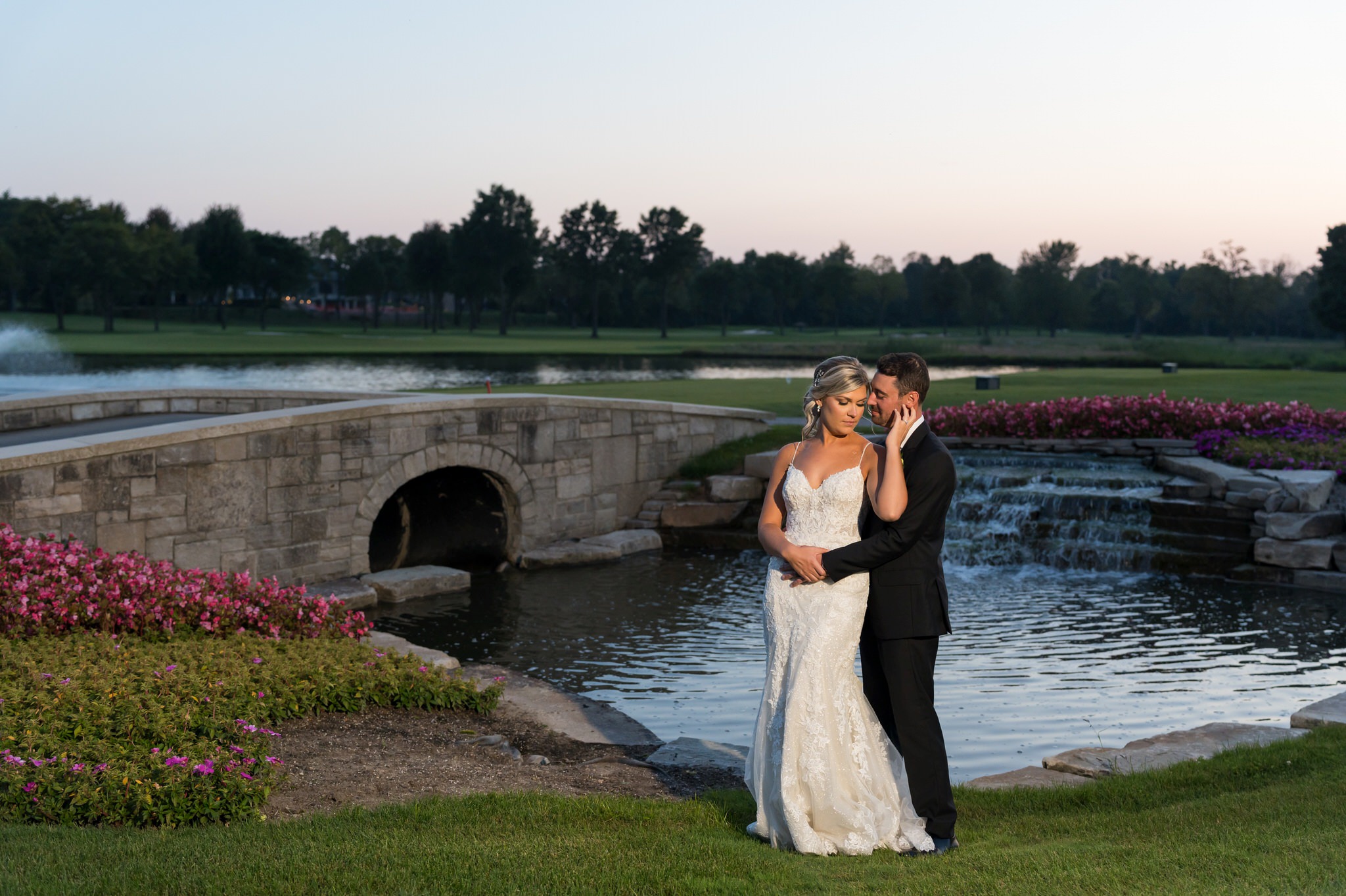 A bride and groom pose on a stone bridge at their Walnut Creek Golf Club wedding in South Lyon, MI.  