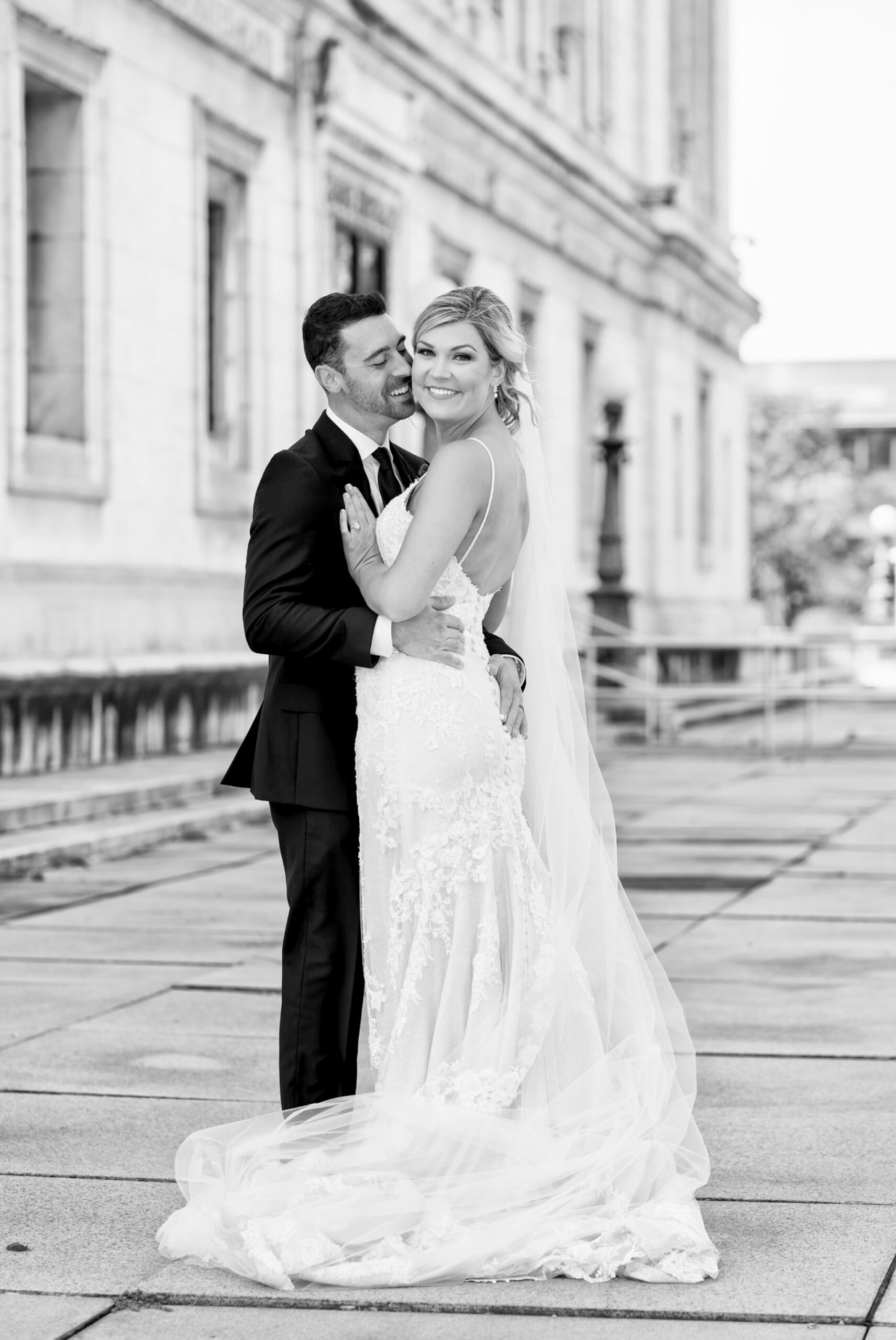 A bride and groom pose on the front porch of the Detroit Public Library on their wedding day.  