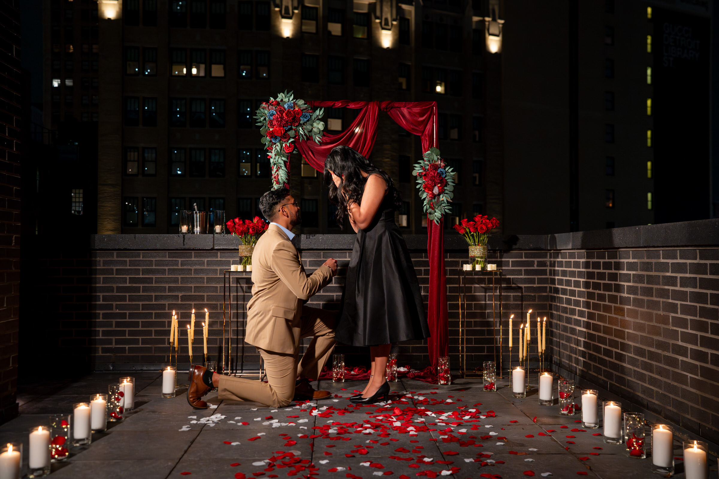 A nighttime, candlelit Shiola Hotel proposal on a rooftop with the Detroit skyline in the background.