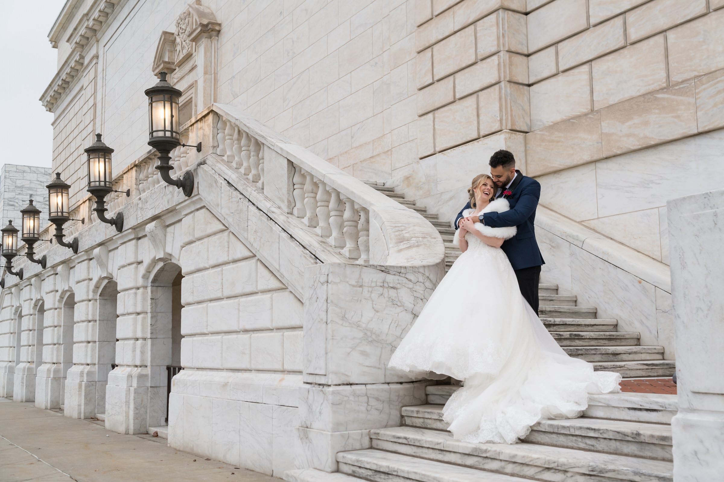 A bride and groom embrace on the steps of the Detroit Public Library on their wedding day.