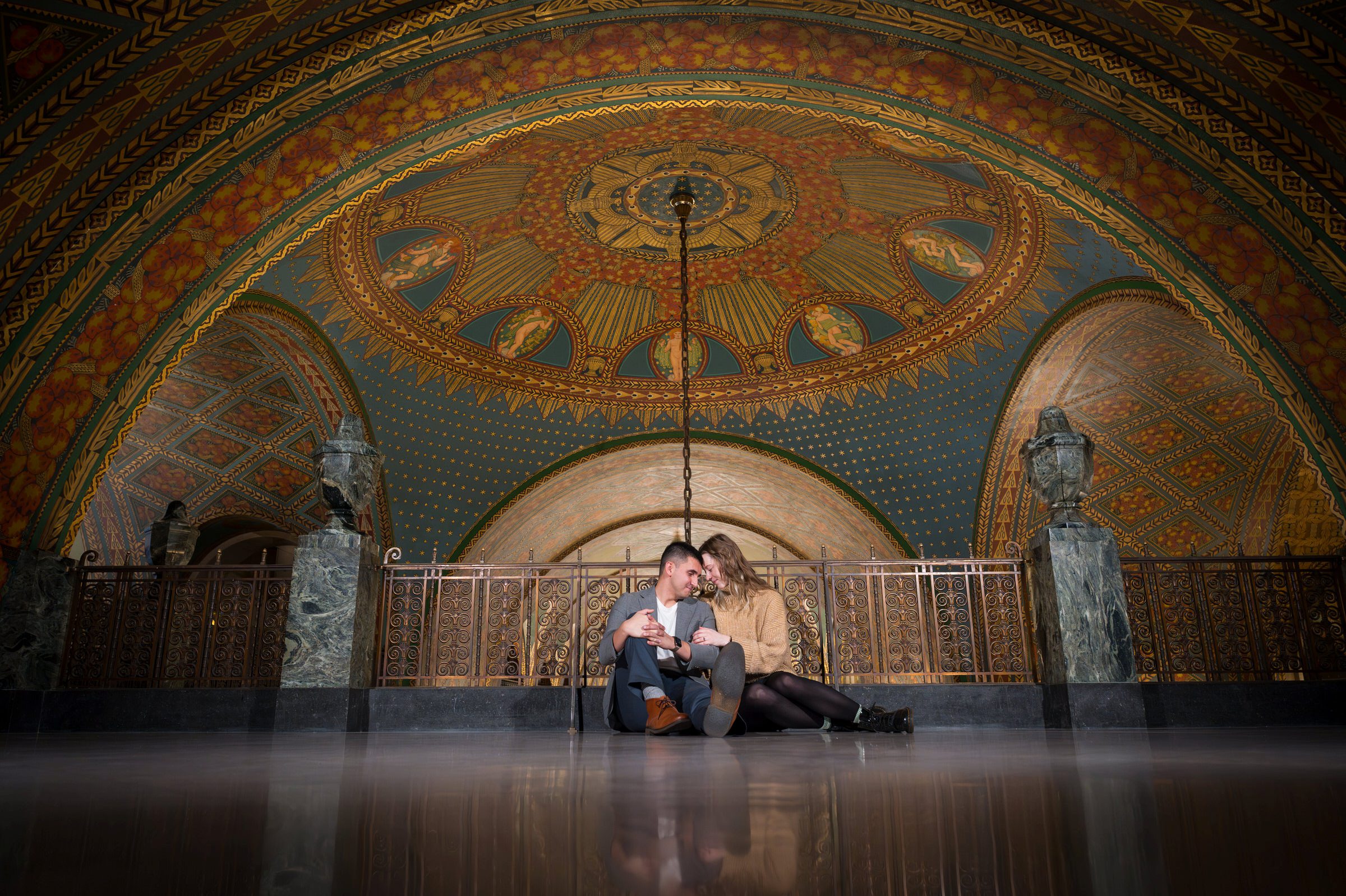 Sitting on the floor, a couple snuggles up moments after their Fisher Building proposal in Detroit, Michigan. 
