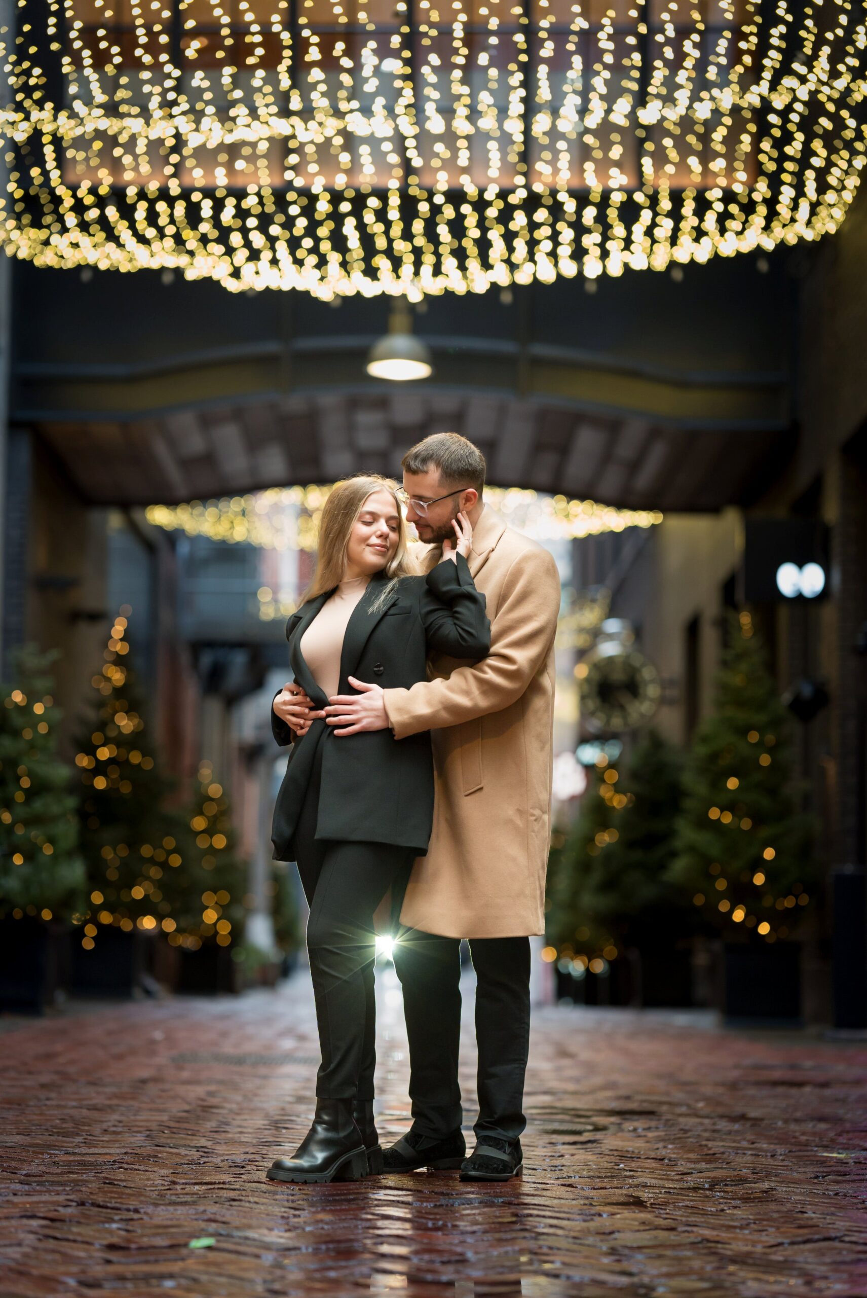 A couple poses under twinkle lights in Parker's Alley following their proposal.  