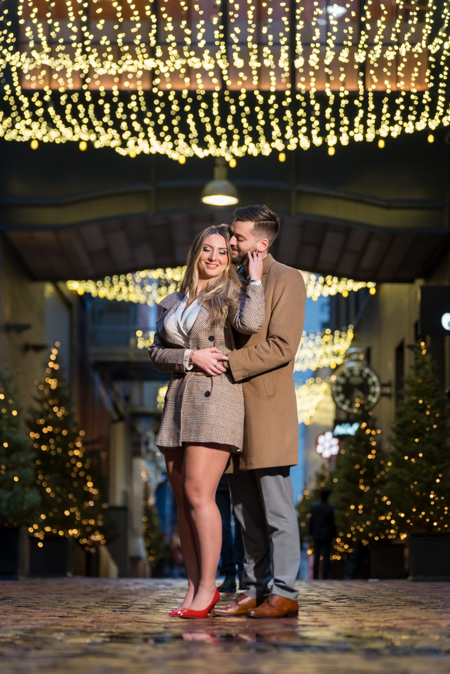 A couple poses under the twinkle lights of Parker's Alley after their proposal. 