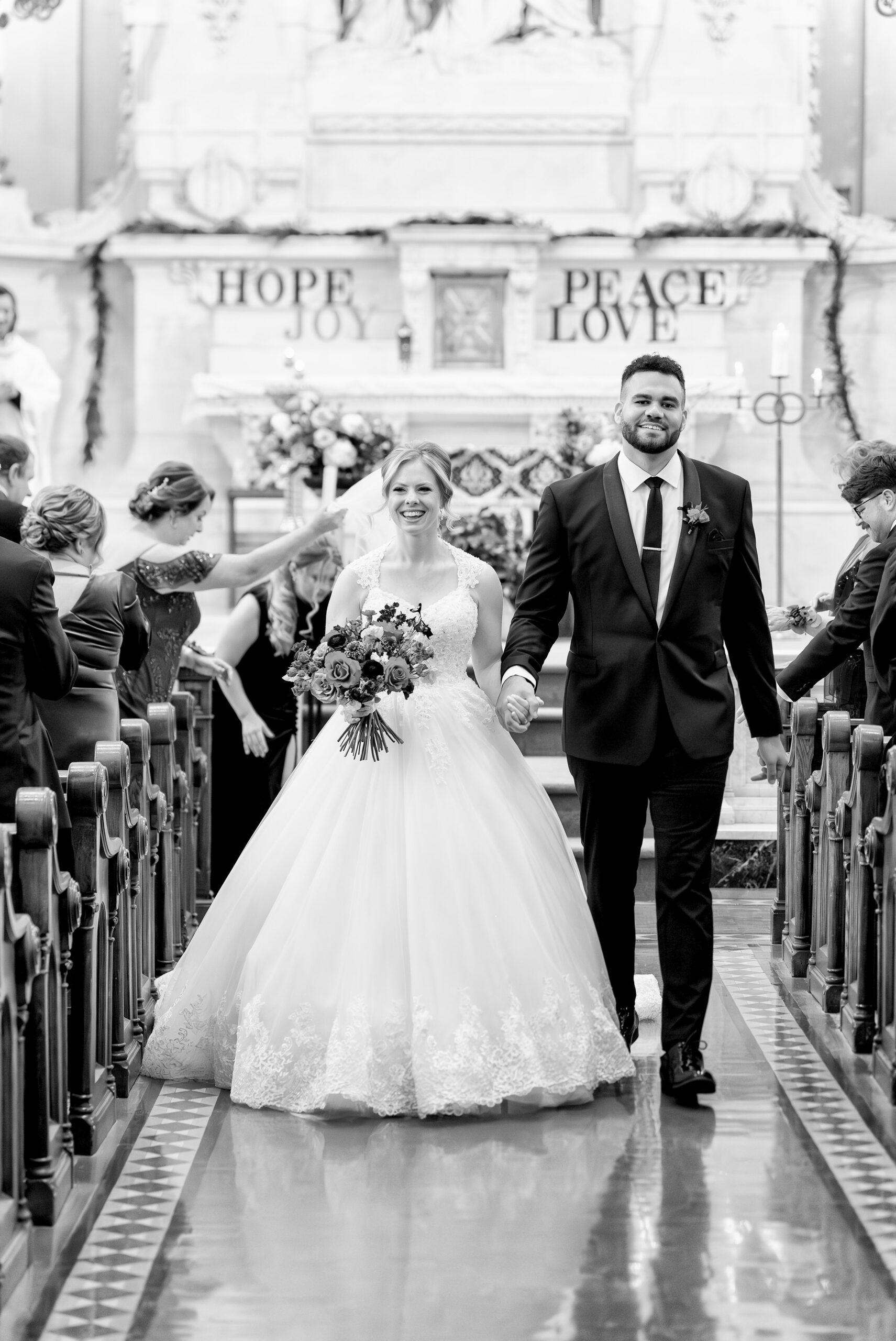 A bride and groom walk down aisle of Sts Peter and Paul Jesuit Church on their wedding day.  