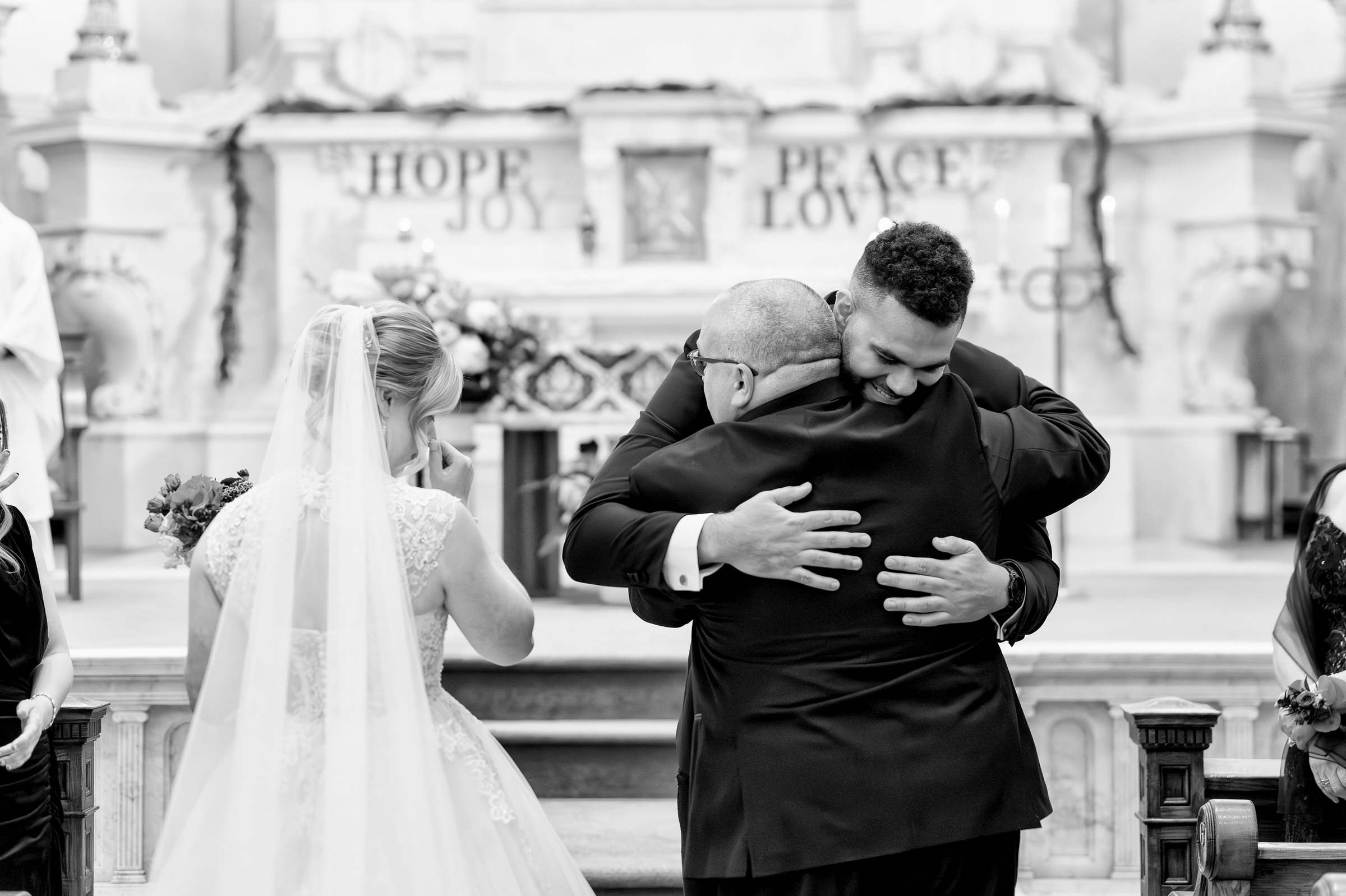 The groom hugs the father of the bride on his wedding day.  