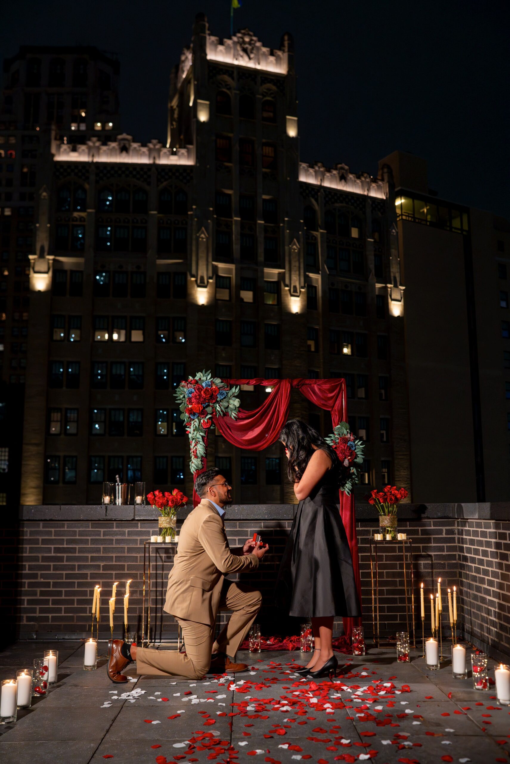 A gentleman takes a knee and pulls out an engagement ring at a rooftop Shinola Hotel proposal. 
