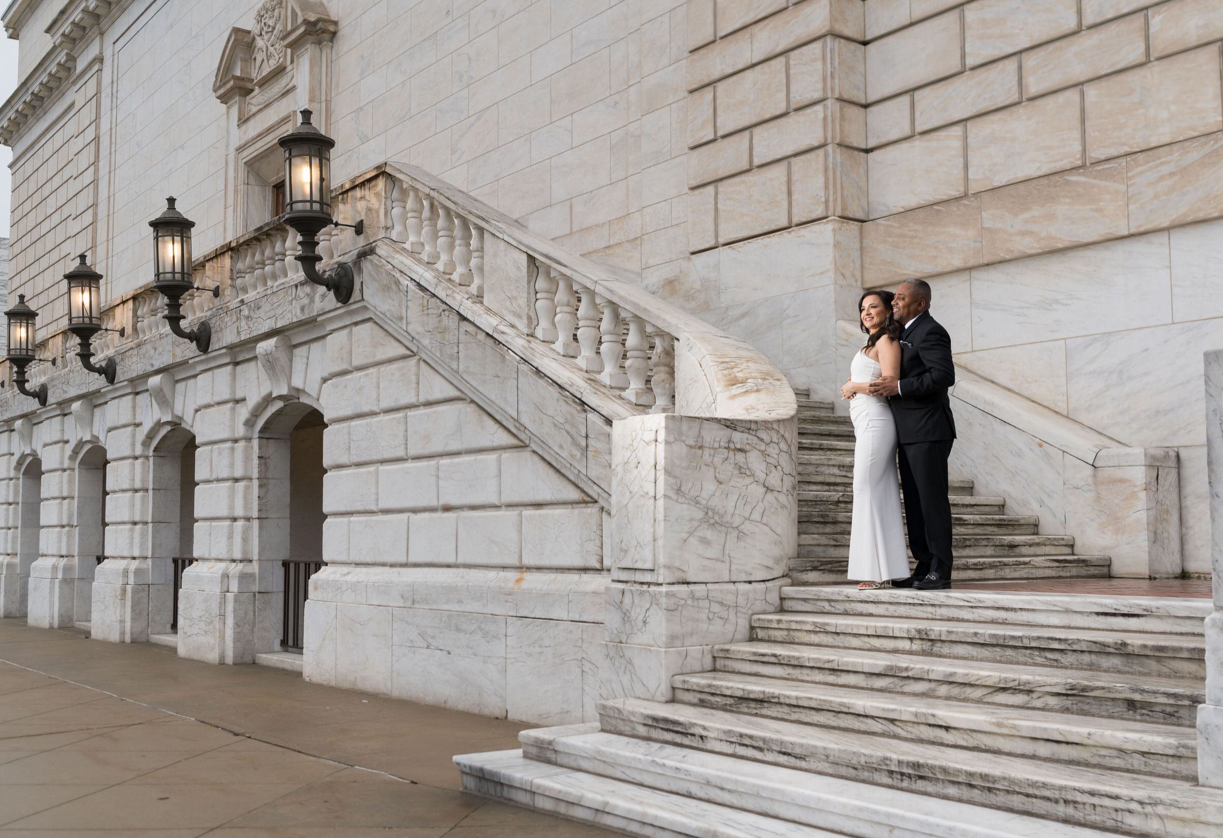 A bride and groom pose on the steps of the Detroit Institute of Arts on their wedding day.  