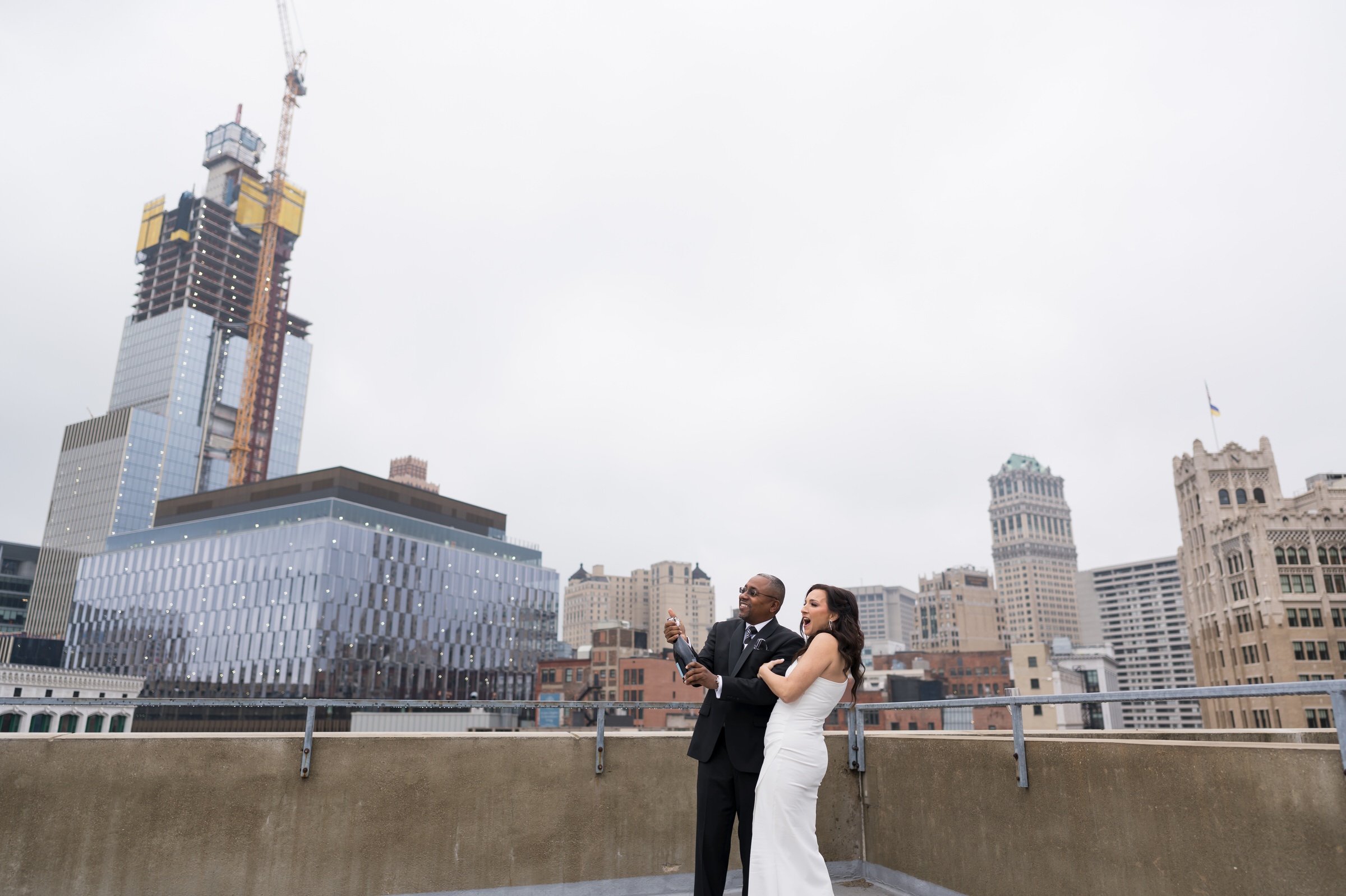A bride and groom pop champagne on the Detroit Opera House parking garage on their wedding day.