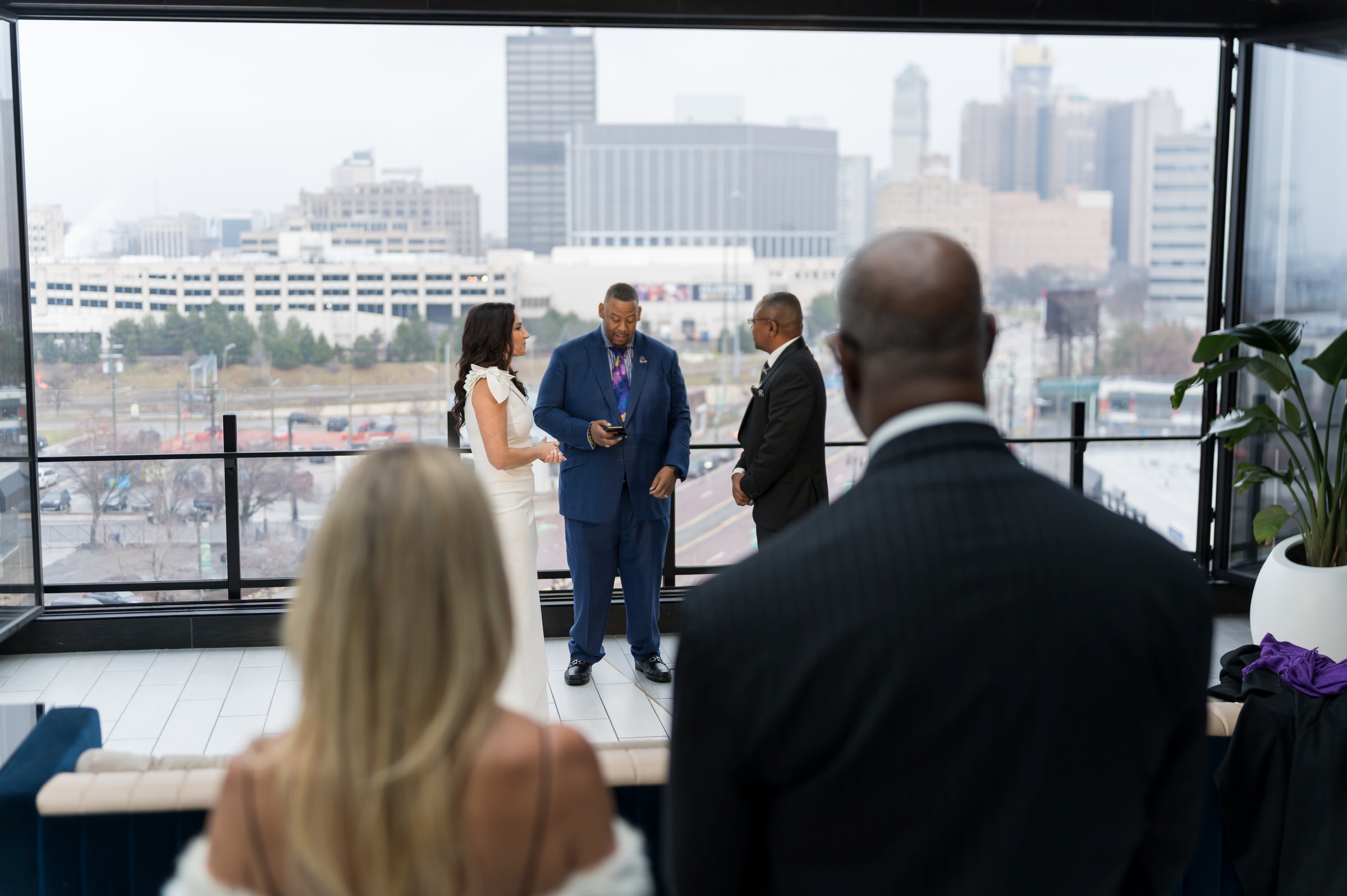 Friends look on as a couple weds in the IO Rooftop Lounge at a Detroit Godfrey Hotel wedding.