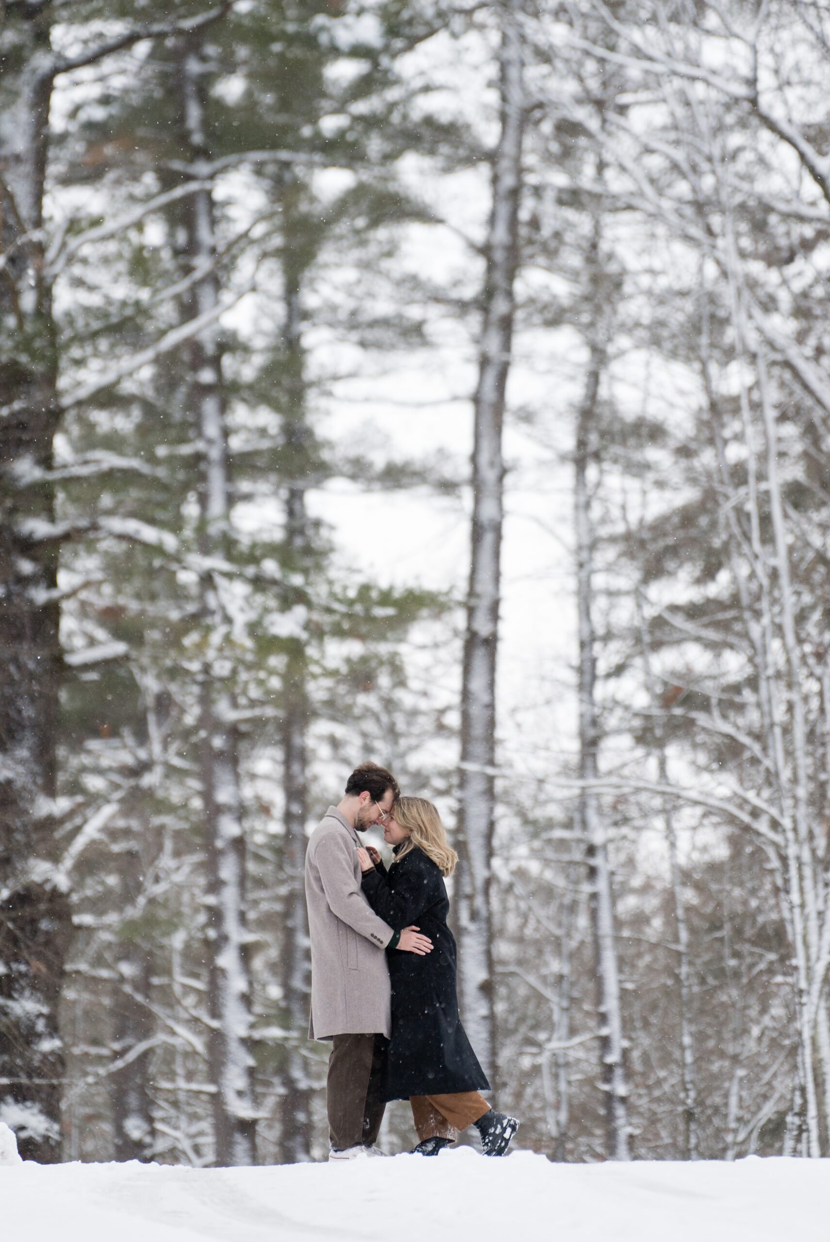 A couple poses along a snow covered walkway after their Getaway proposal