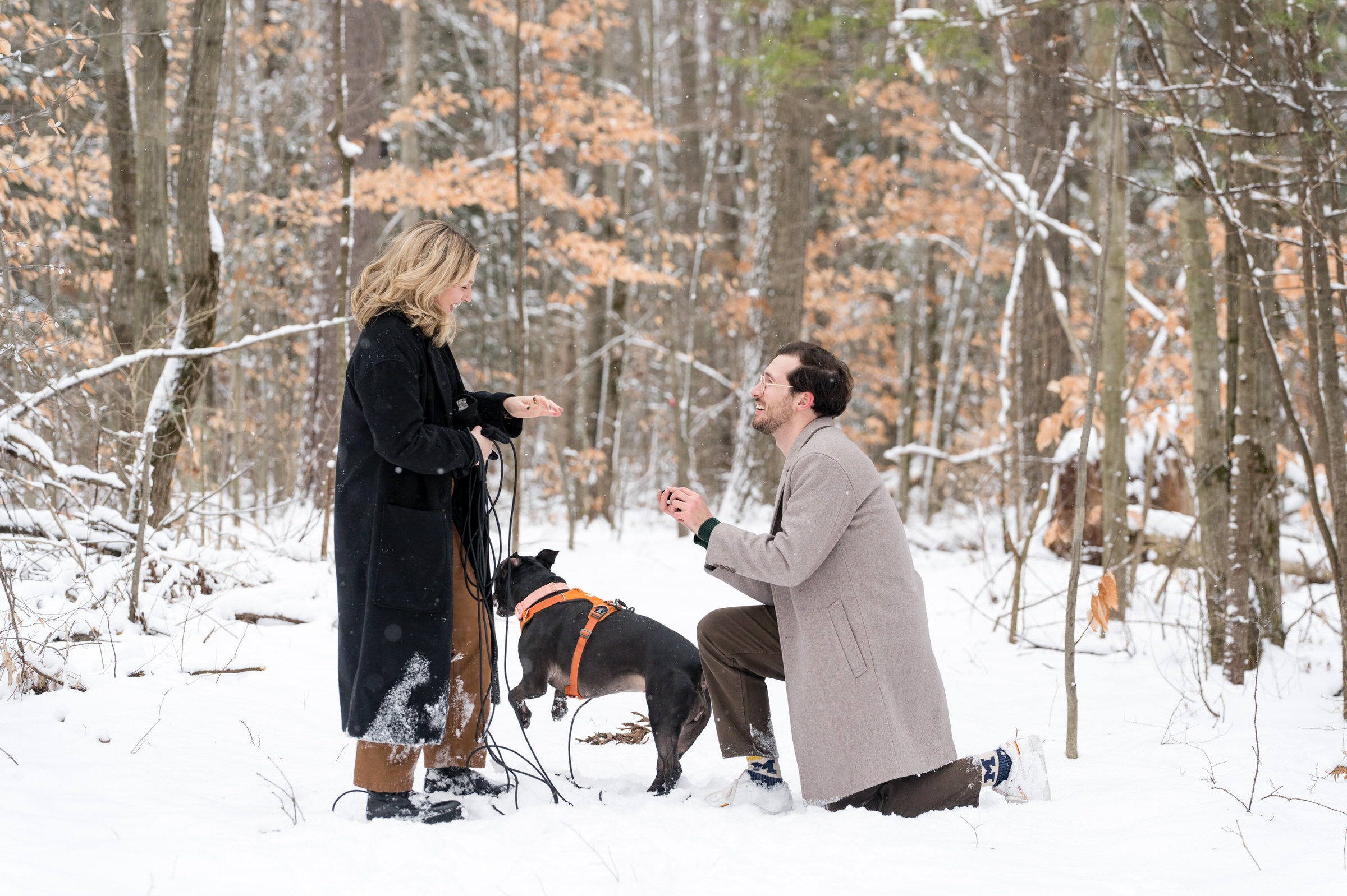 A gentleman stops and proposes in the middle of a snow covered walking path.  