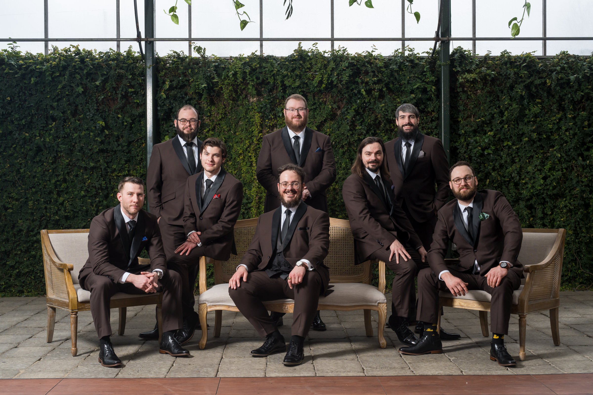 The groom sits surrounded by his groomsmen at his Planterra wedding. 