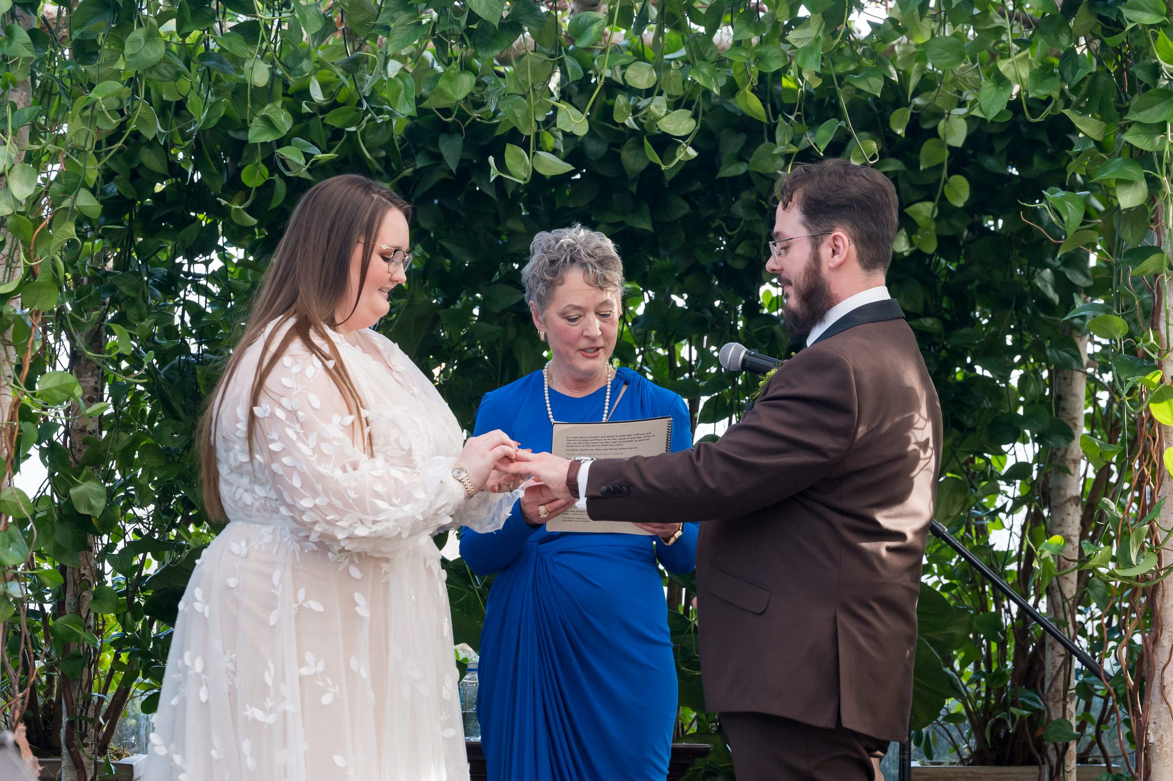 A bride and groom exchange rings during their Planterra wedding ceremony.   