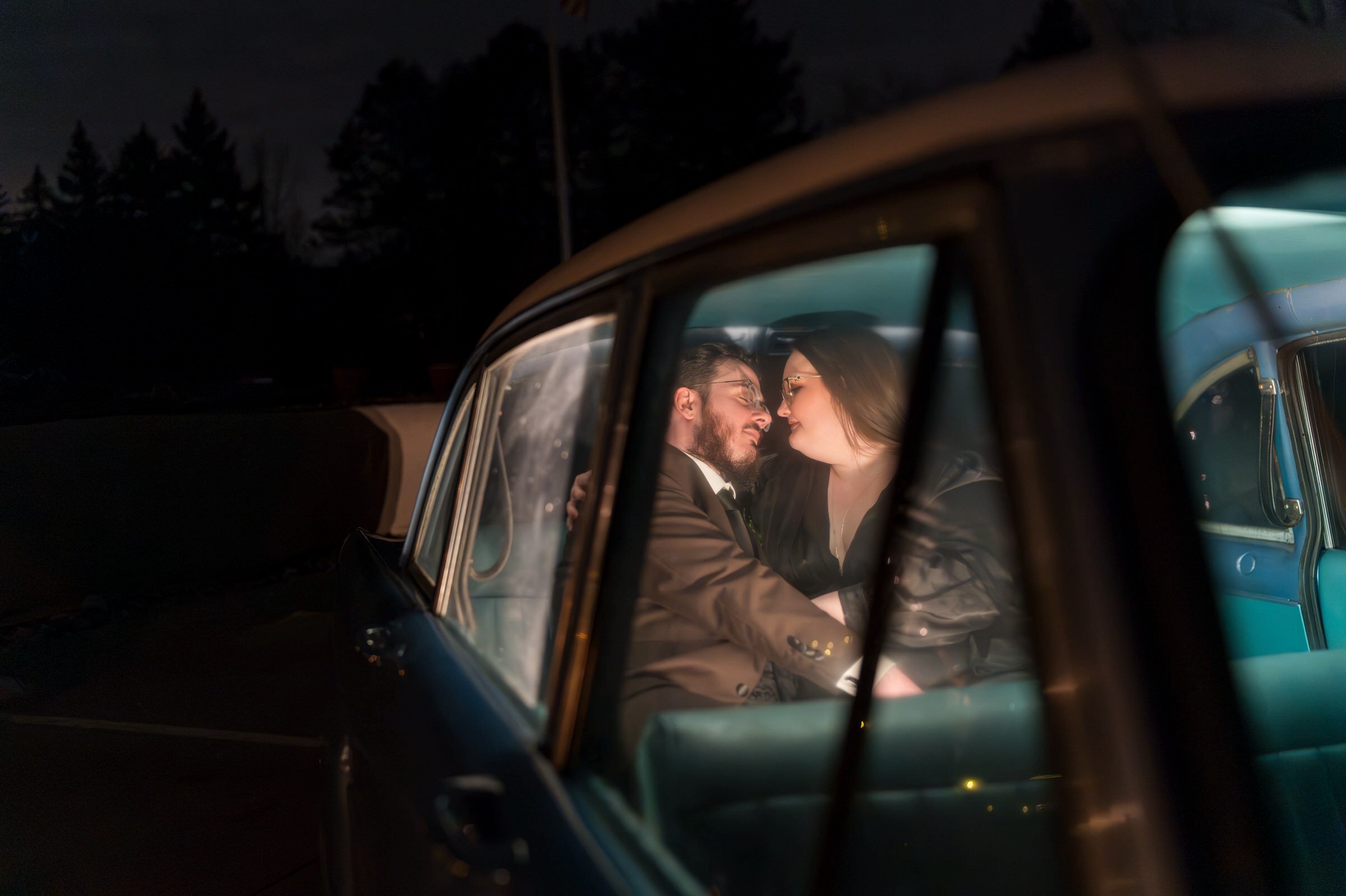 A couple snuggles in the back of a blue Checker car outside of their Planterra wedding.  