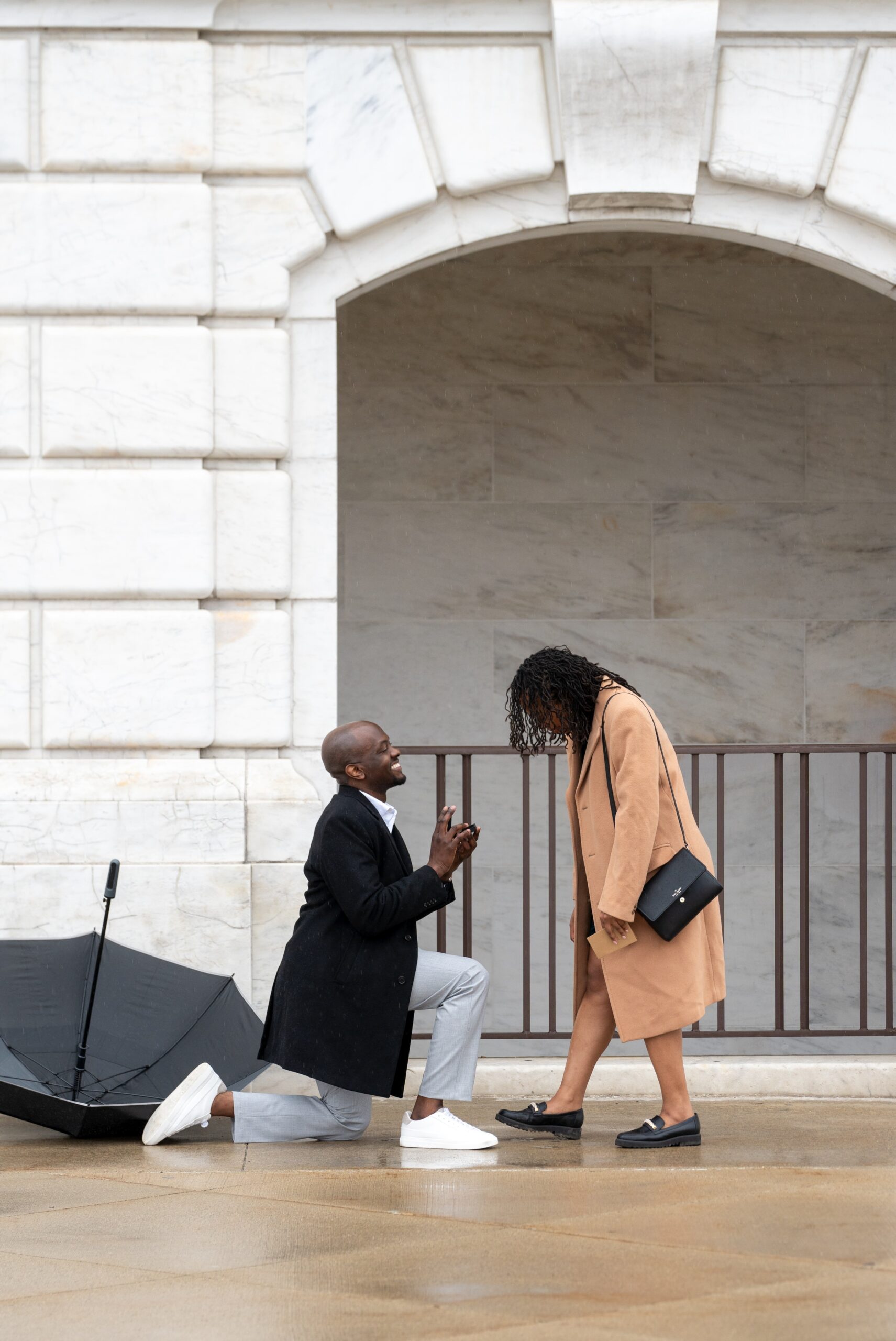 A gentleman takes a knee during his marriage proposal at the DIA in the rain.  