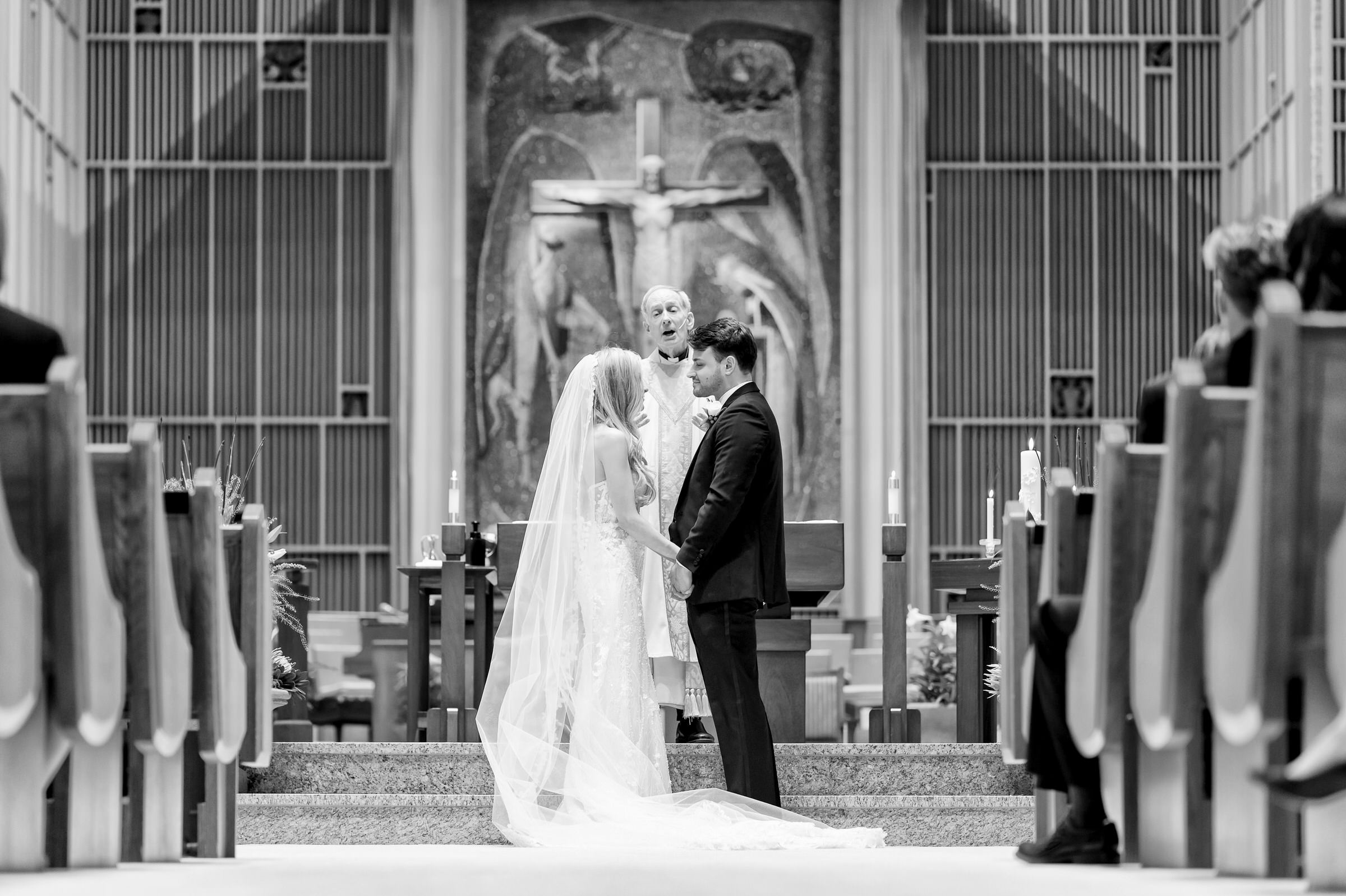 A bride and groom stand at the front of Holy Name Church during their wedding vows.  