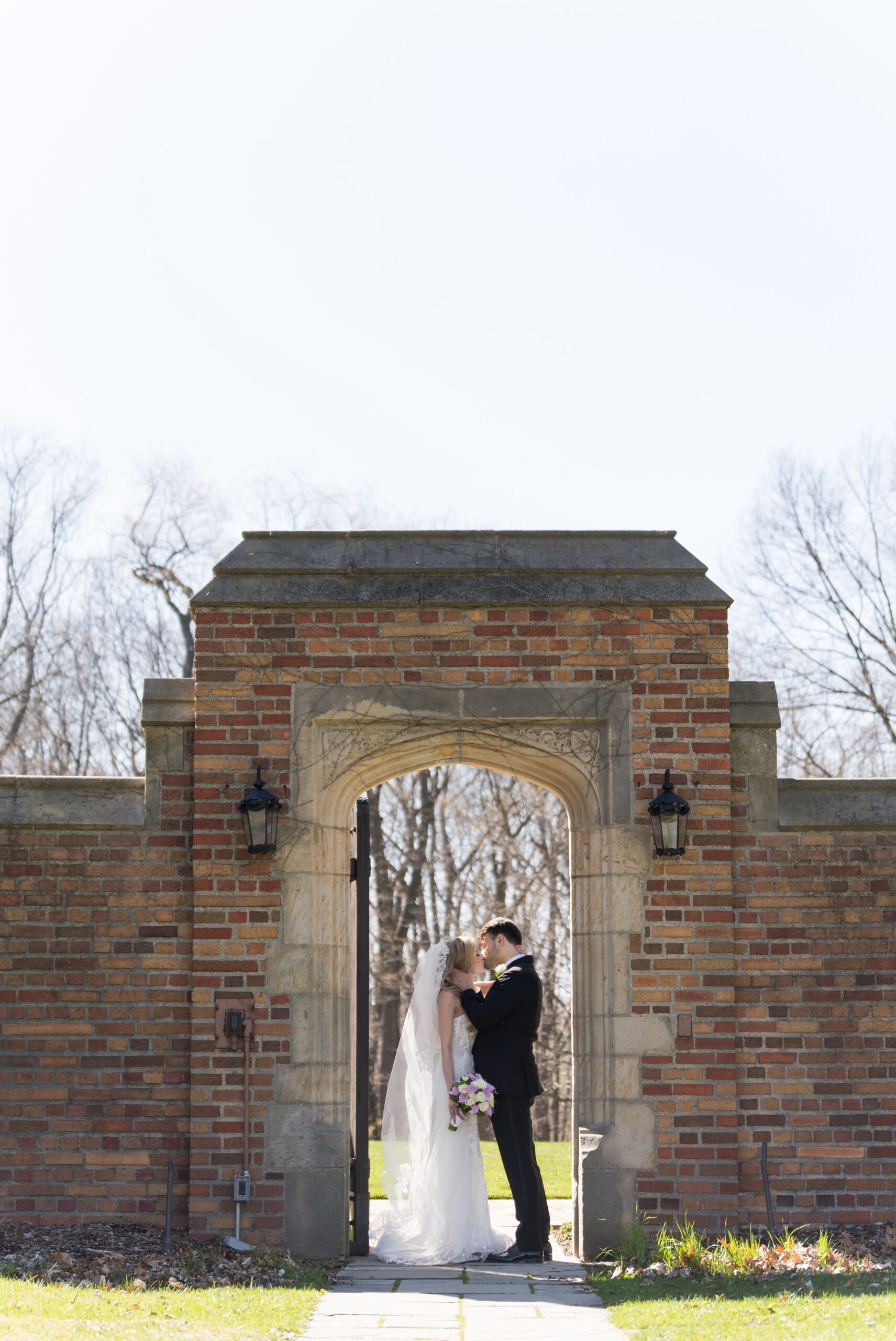 A bride and groom kiss under an arched doorway at their Meadowbrook wedding.  