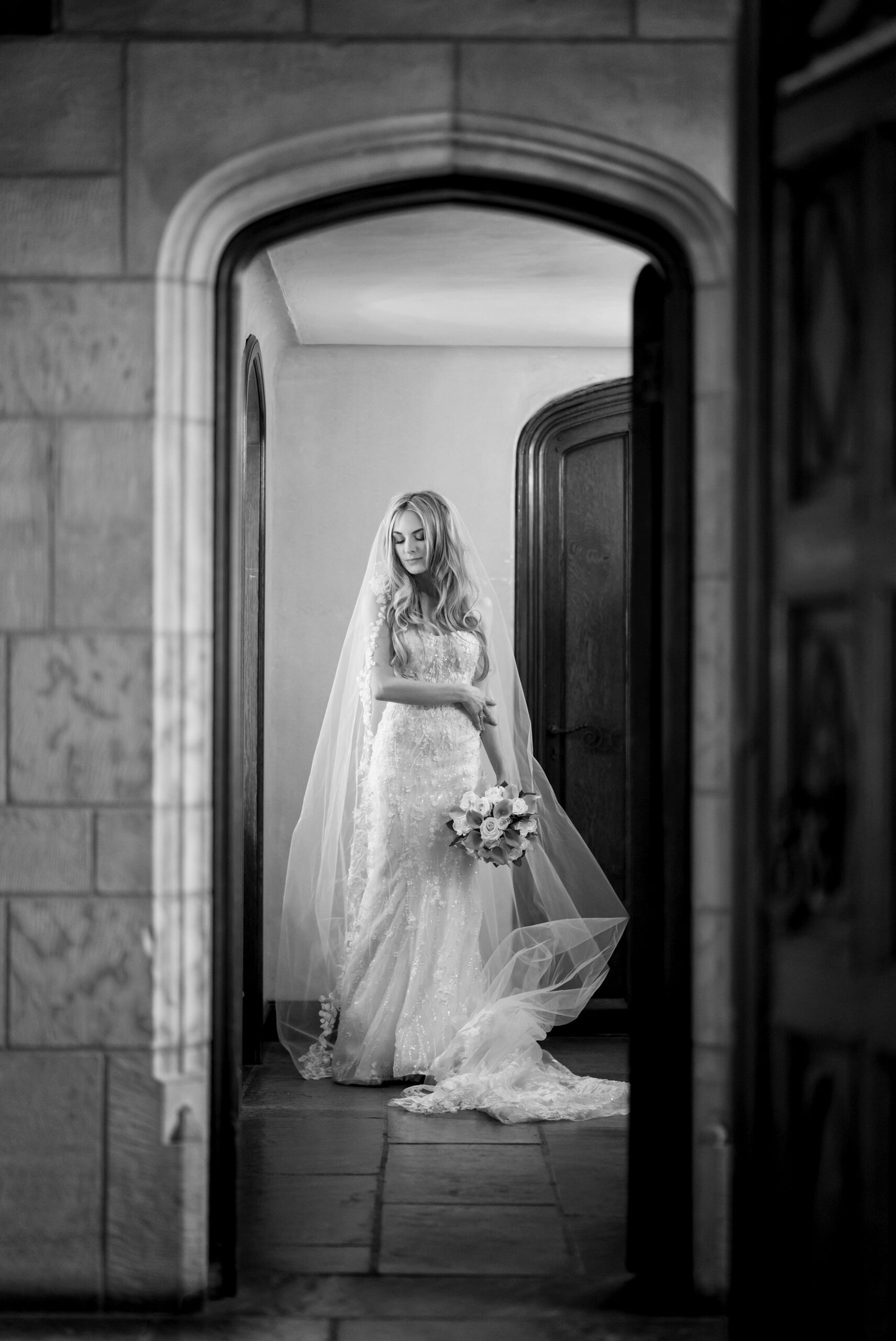 A bride looks at herself in a mirror while standing in an archway at her Meadowbrook wedding reception.  