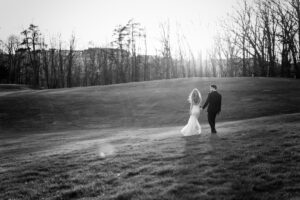 Couple walks down a hill during golden hour at a Meadowbrook wedding