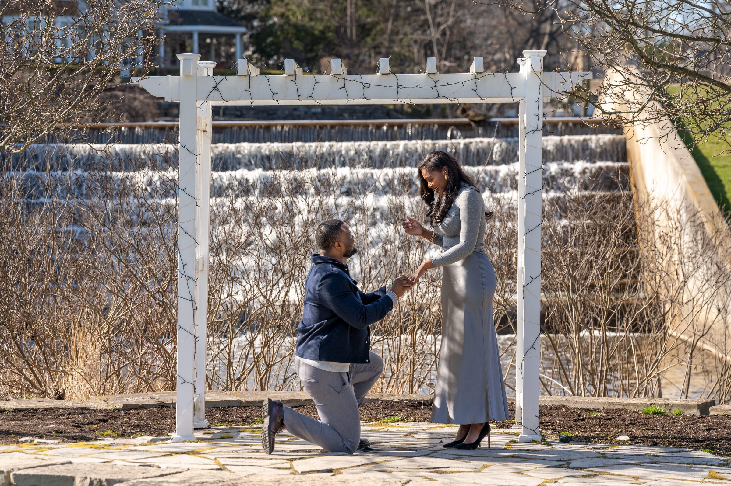 A fiancee asks for his girlfriend's hand in marriage at a proposal at Quarton Lake pergola.  