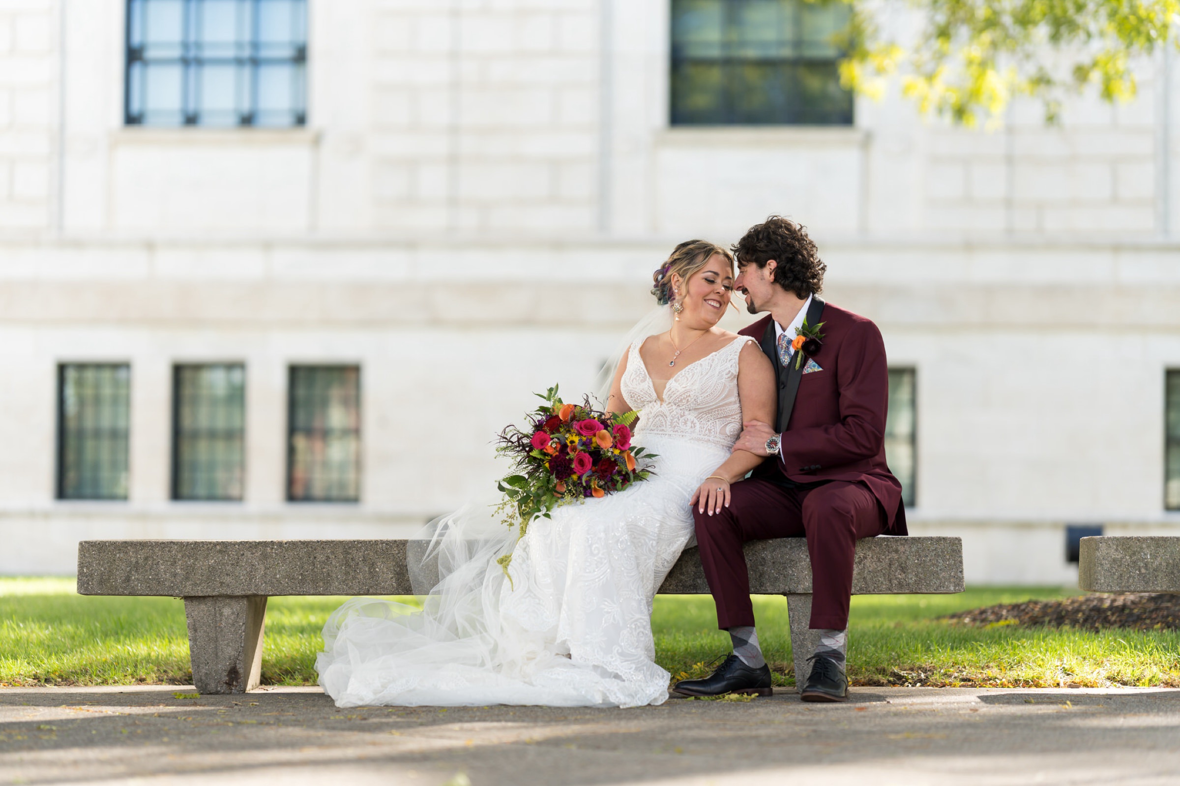 A bride and groom sit outside of the DIA on their wedding day.  