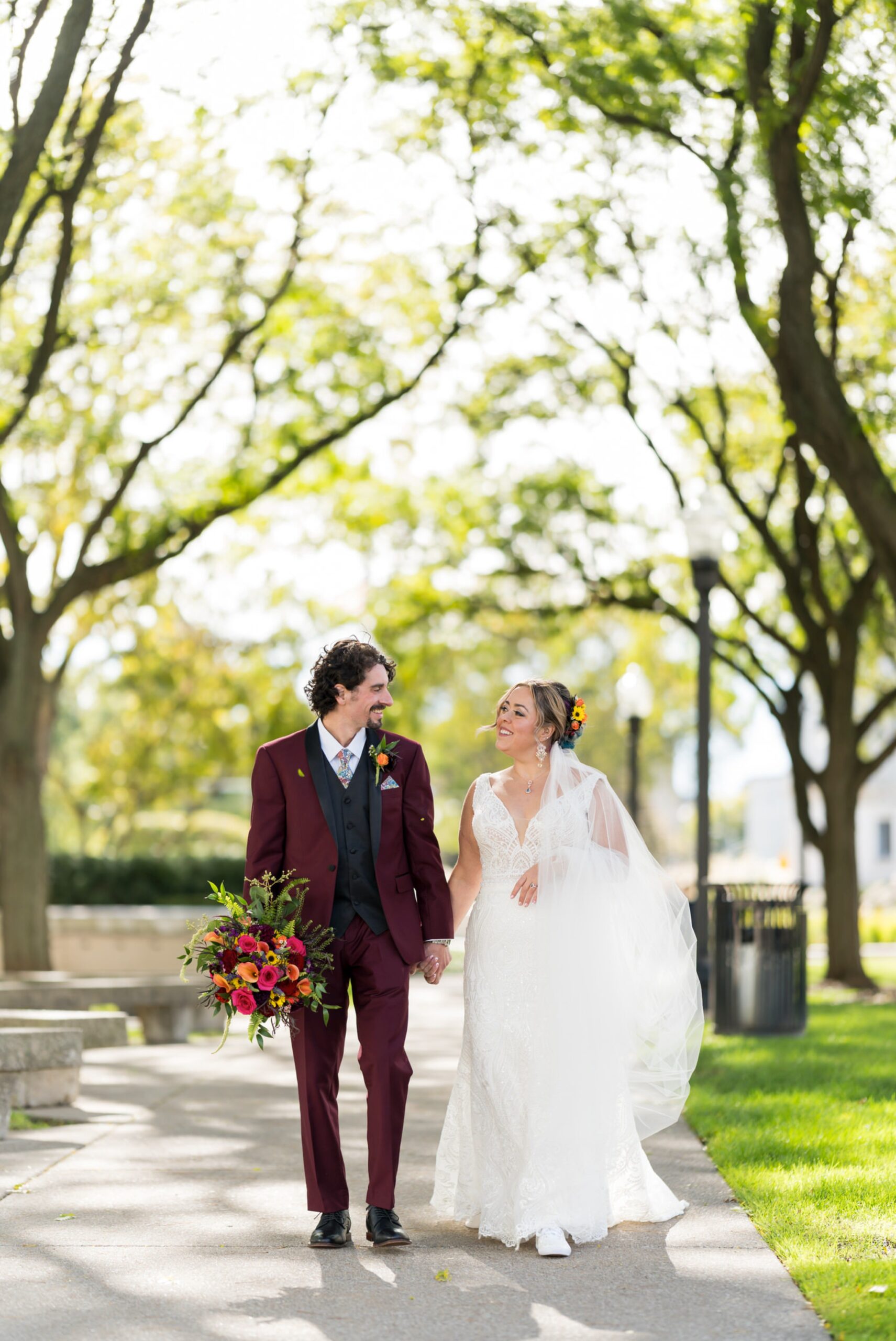 A bride and groom hold hands and walk outside of the DIA on their wedding day.  