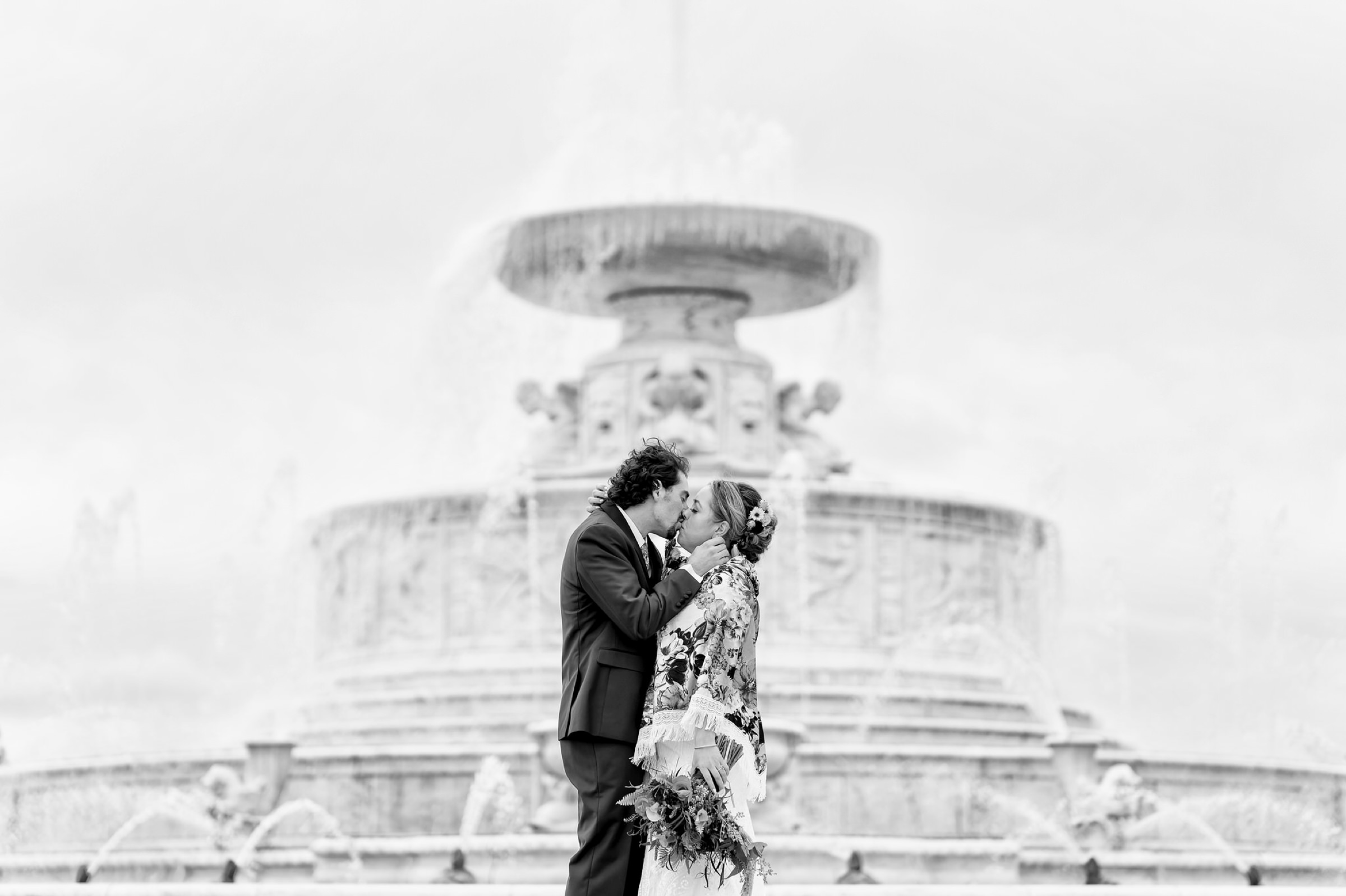 A bride and groom kiss in front of the Fountain on Belle Isle on their wedding day.  