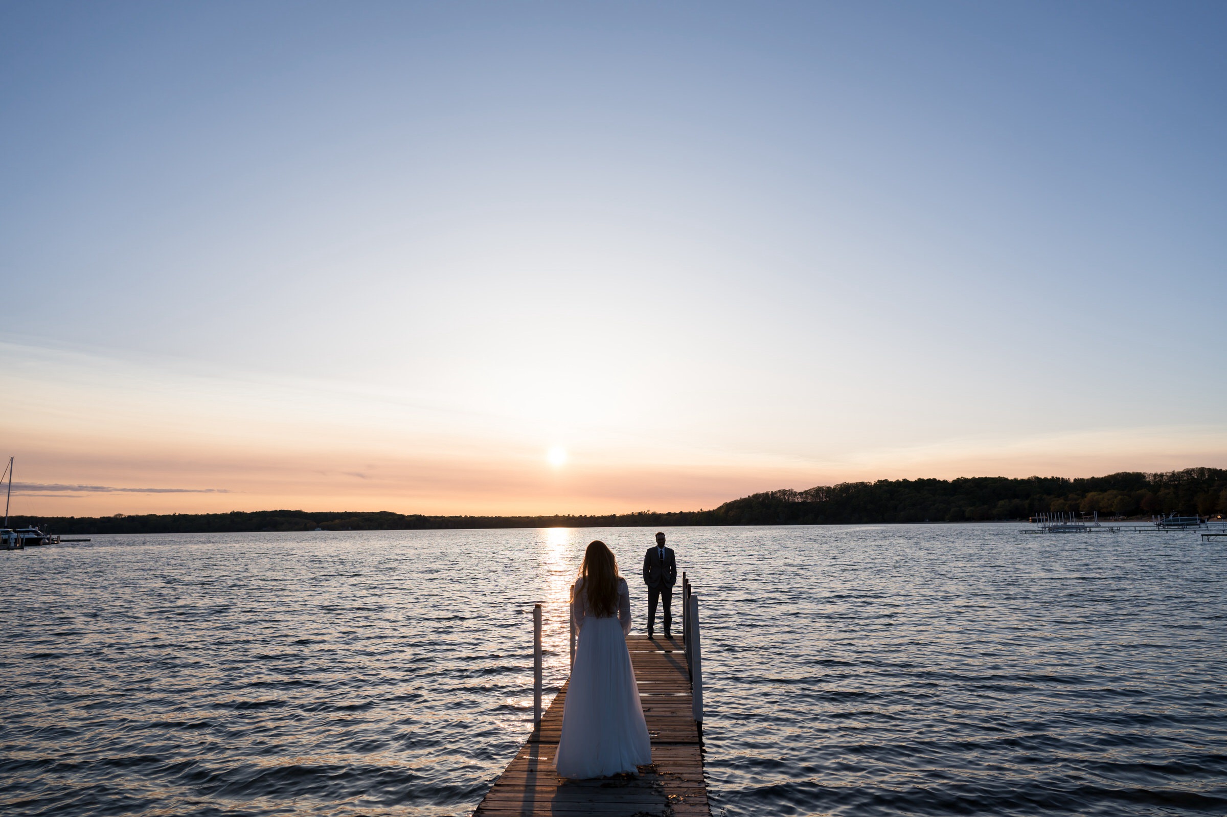 A bride faces here groom on a dock at their Traverse City wedding.  