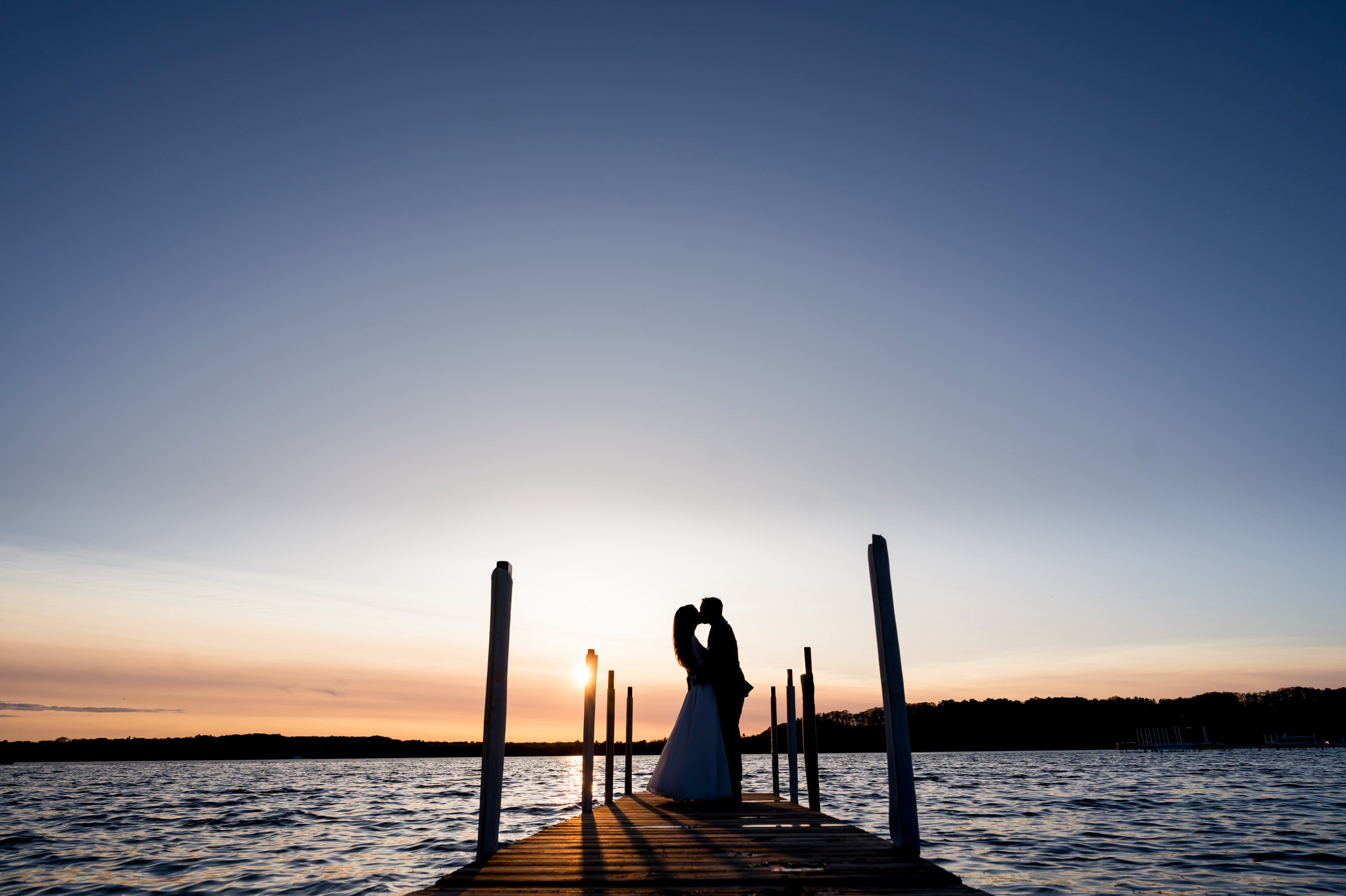Newlyweds kiss on a dock at sunset during their Traverse City wedding.  
