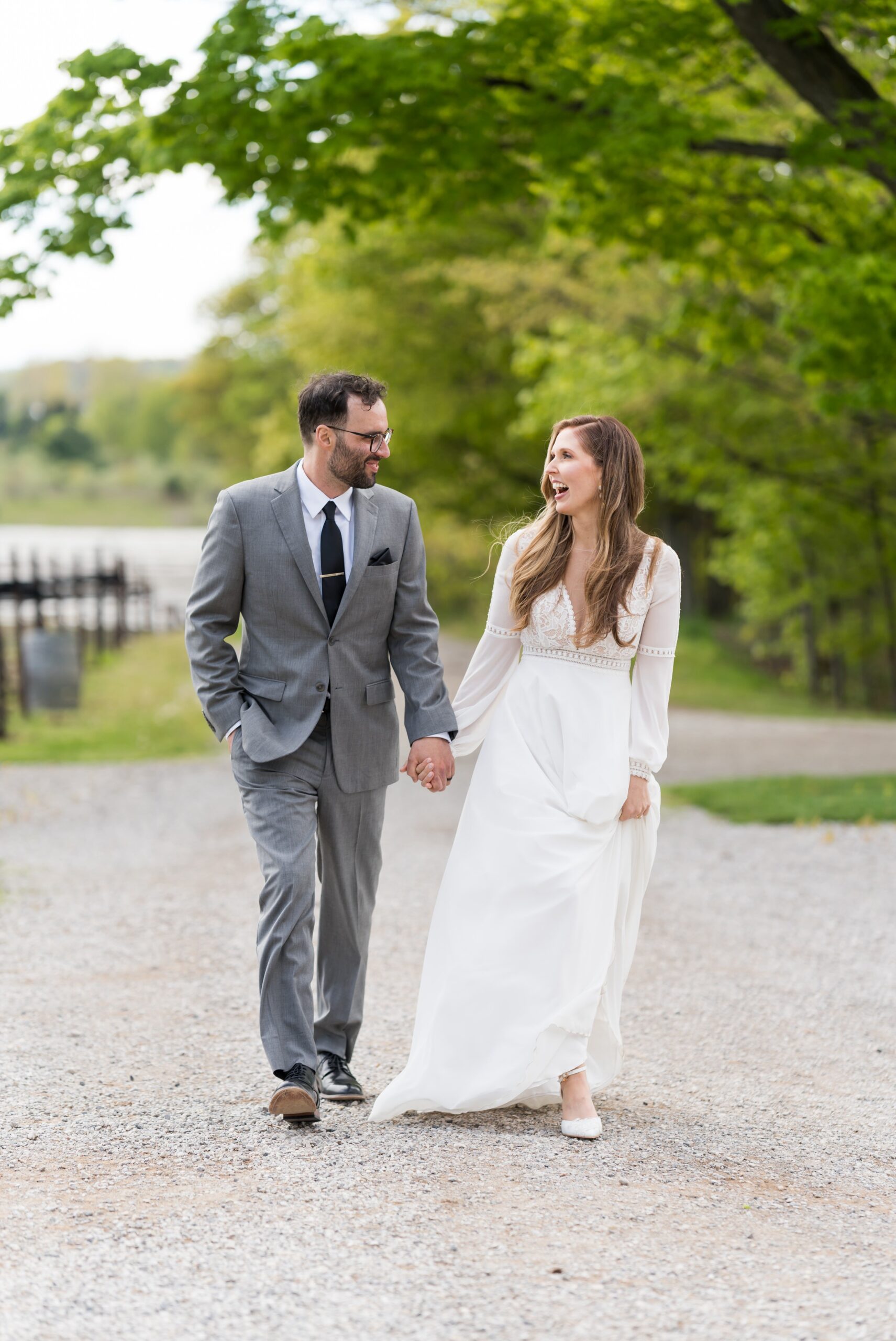 A bride and groom walk hand in hand at vineyard during their Traverse City wedding.  