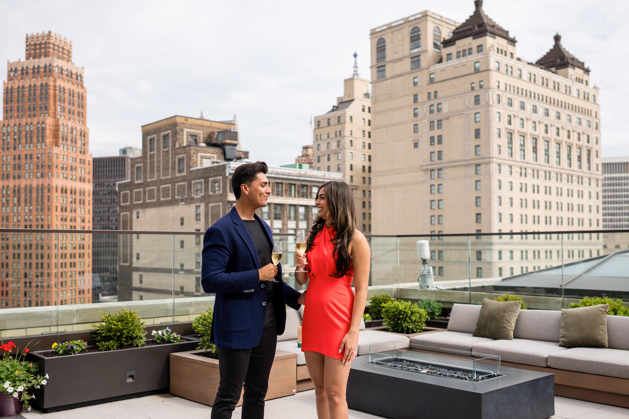 A couple shares a glass of champagne following their beautiful Kamper's Rooftop Proposal atop the Book Tower in Detroit.  