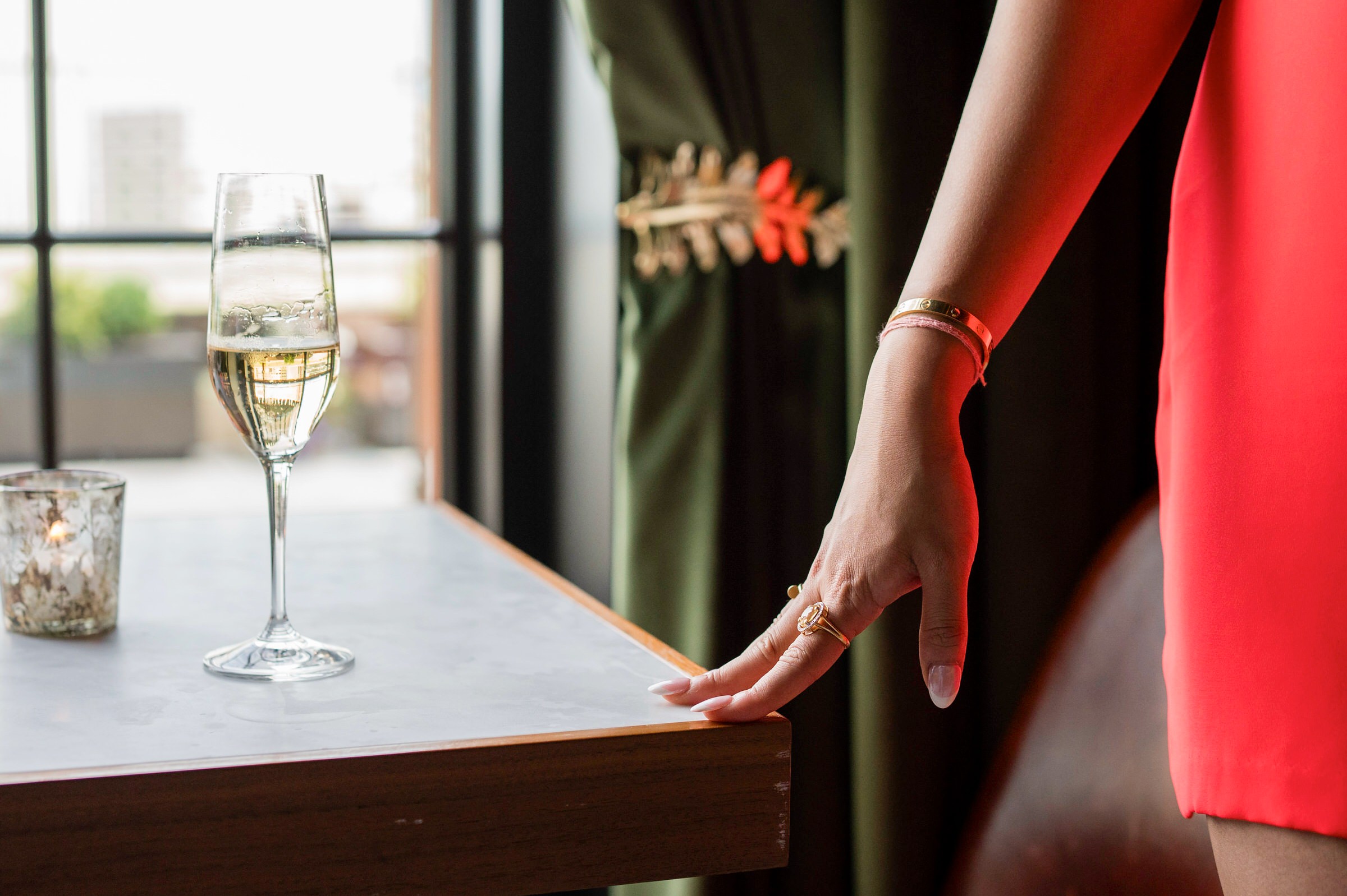 A detail shot of a glass of champagne and a graceful hand along the edge of a table at a Book Tower engagement session.  