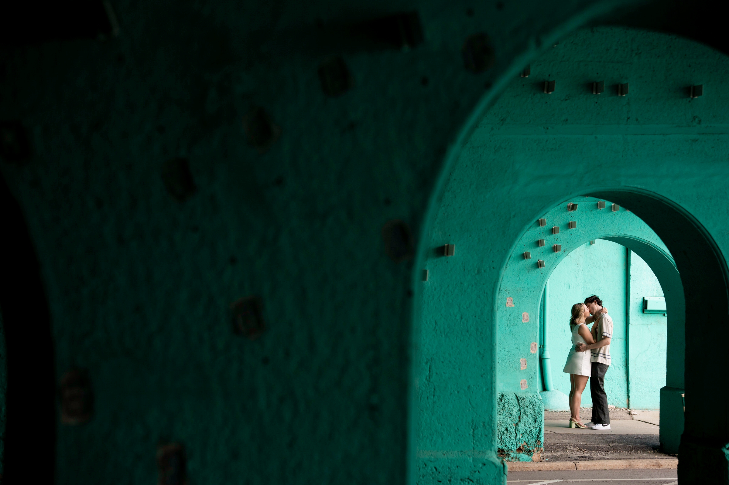 Couple kisses under a colorful arch during their Detroit lifestyle engagement session.  