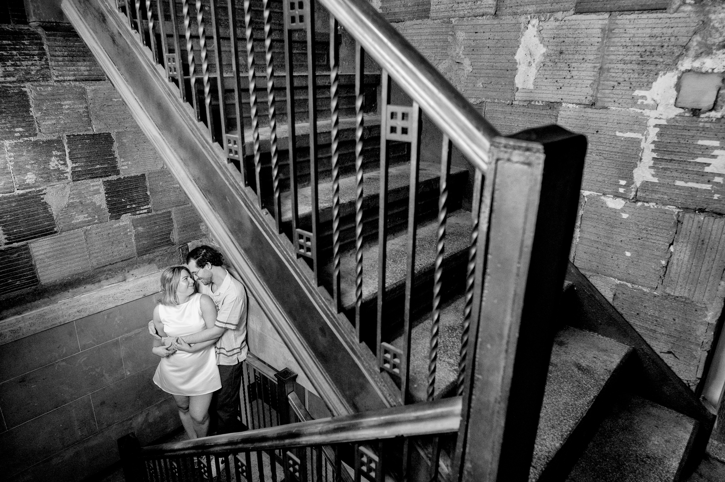 Couple hugs in the stairwell of the Detroit lifestyle engagement session. 