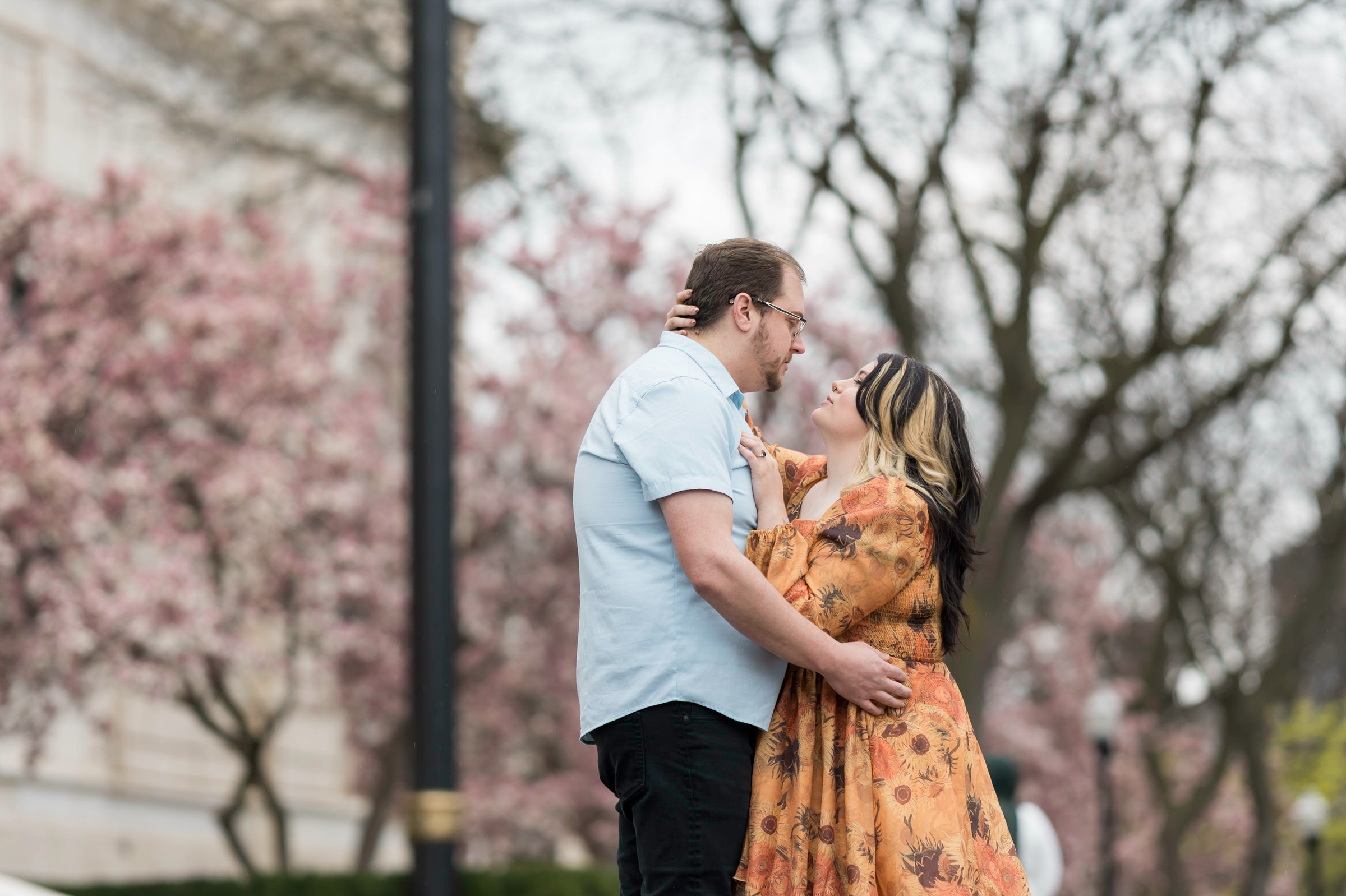 Darren and Manna embrace outside of DIA with magnolia tree in background 