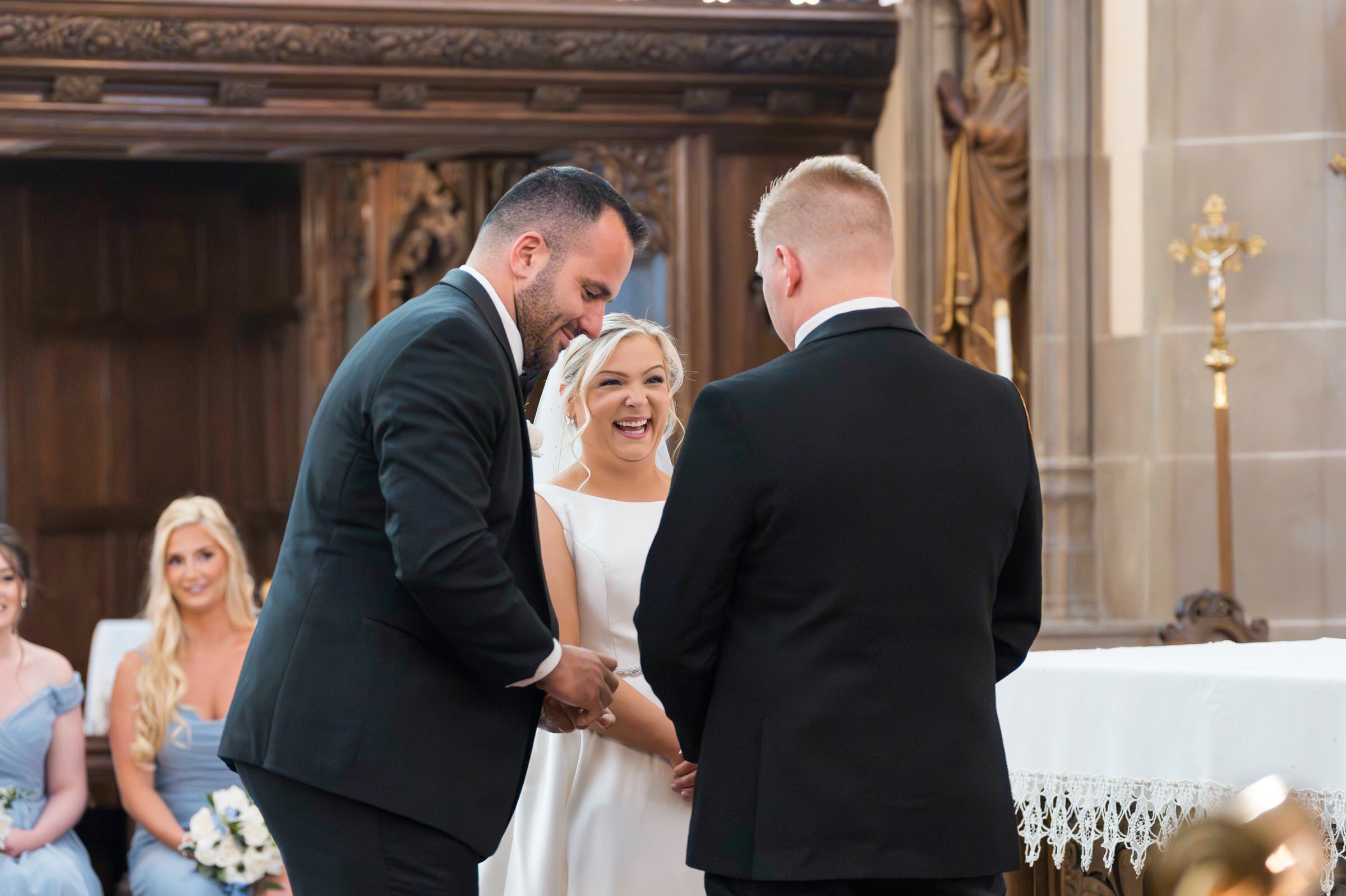Bride laughs during ring exchange with groom and best man 