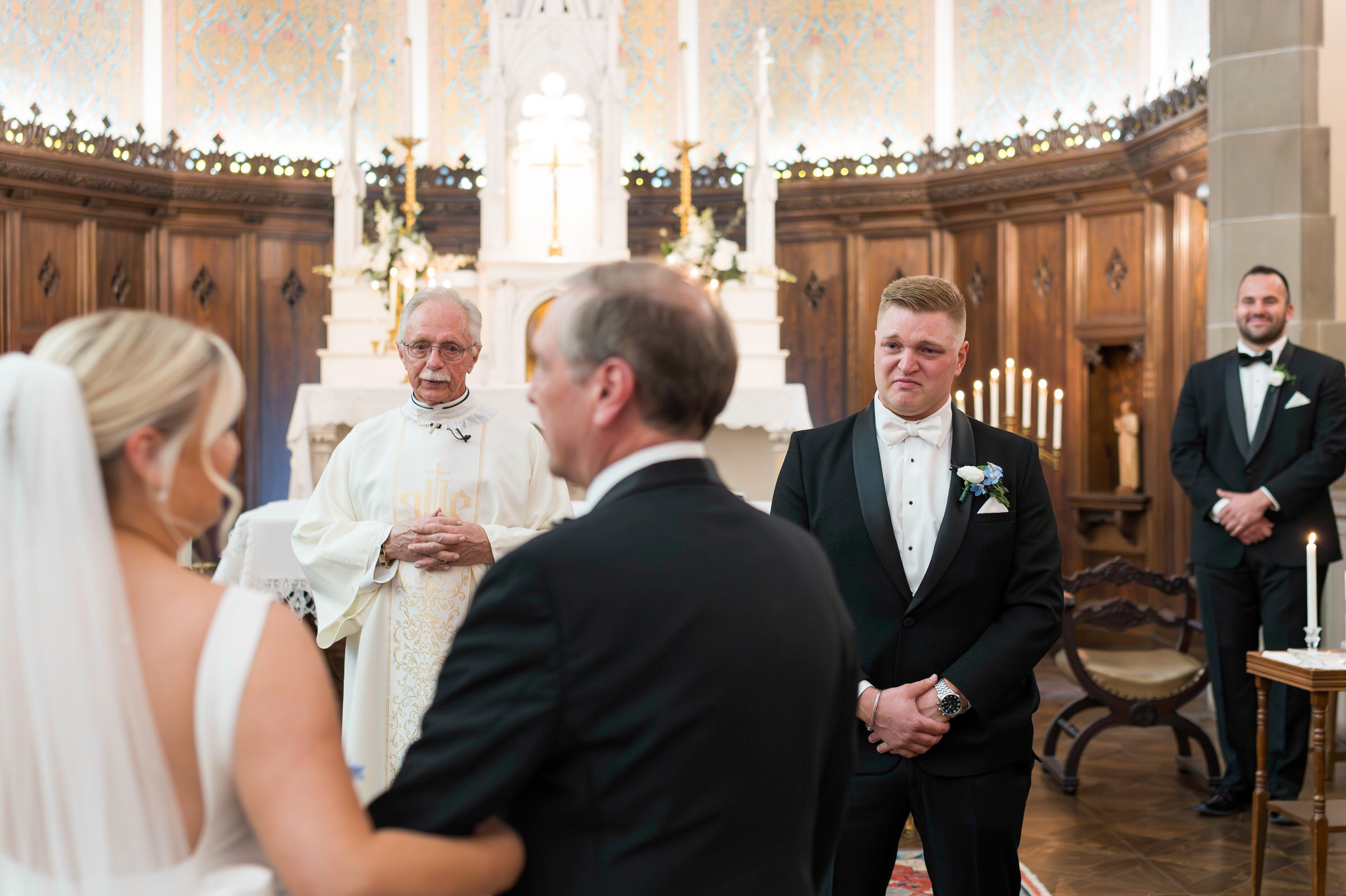 Groom watches bride and dad hug 