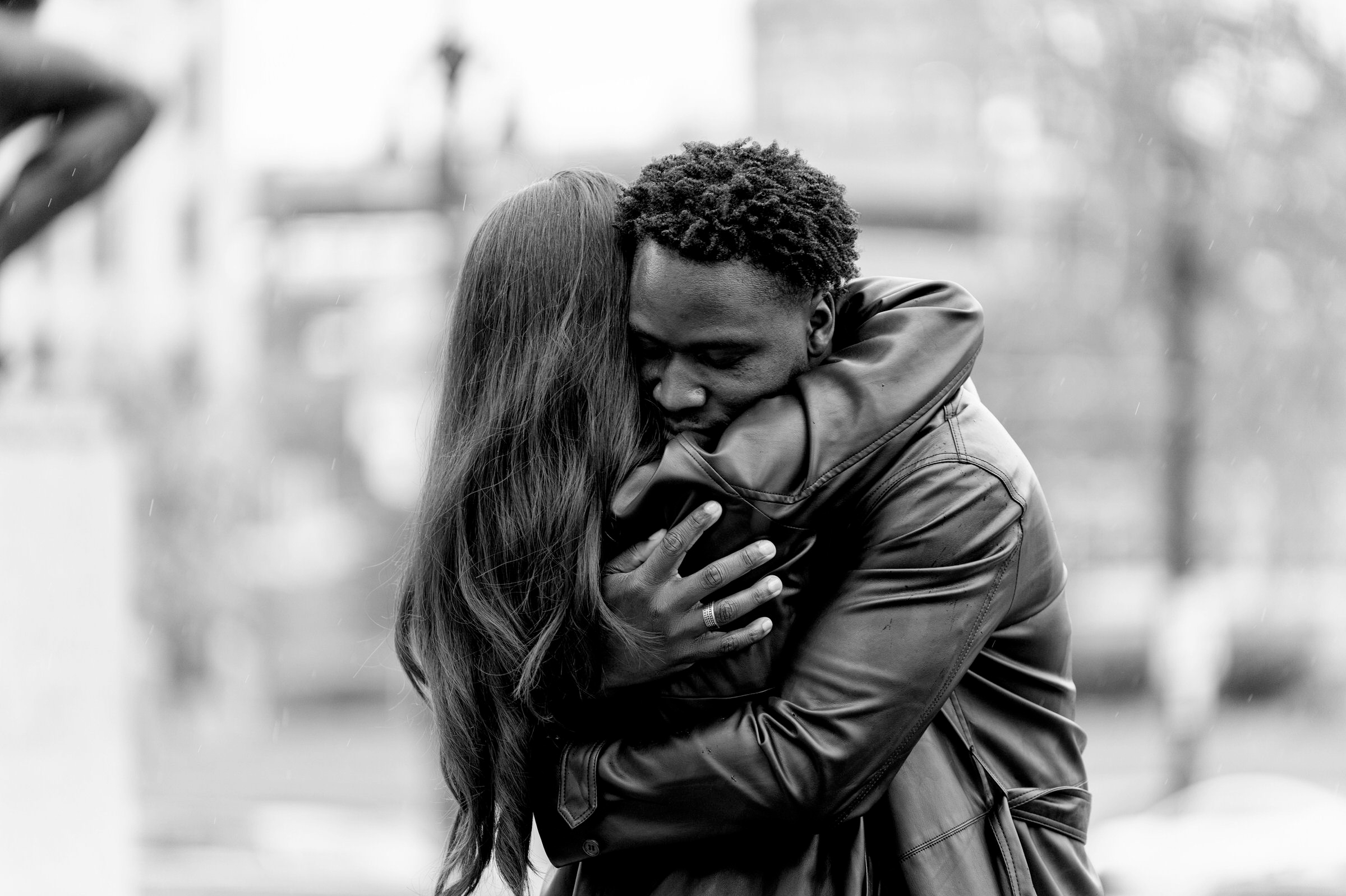 Man and woman embrace after during rainy proposal at Detroit Institute of Arts 