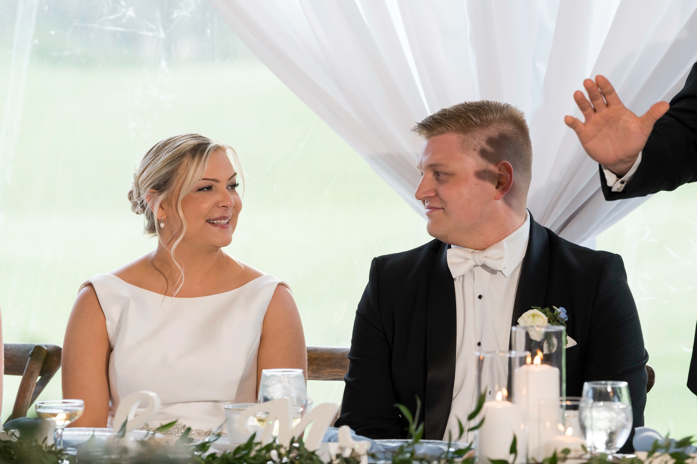 Bride and groom look at each other during best man's speech 