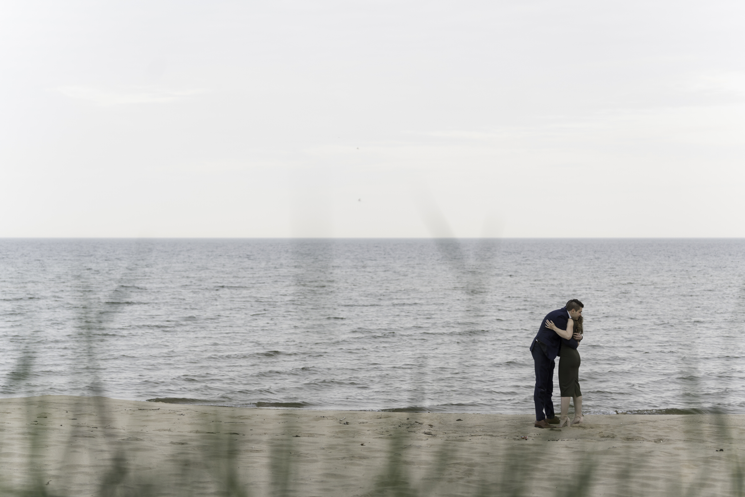 Couple embrace with a hug during proposal on the Shores of Oscoda