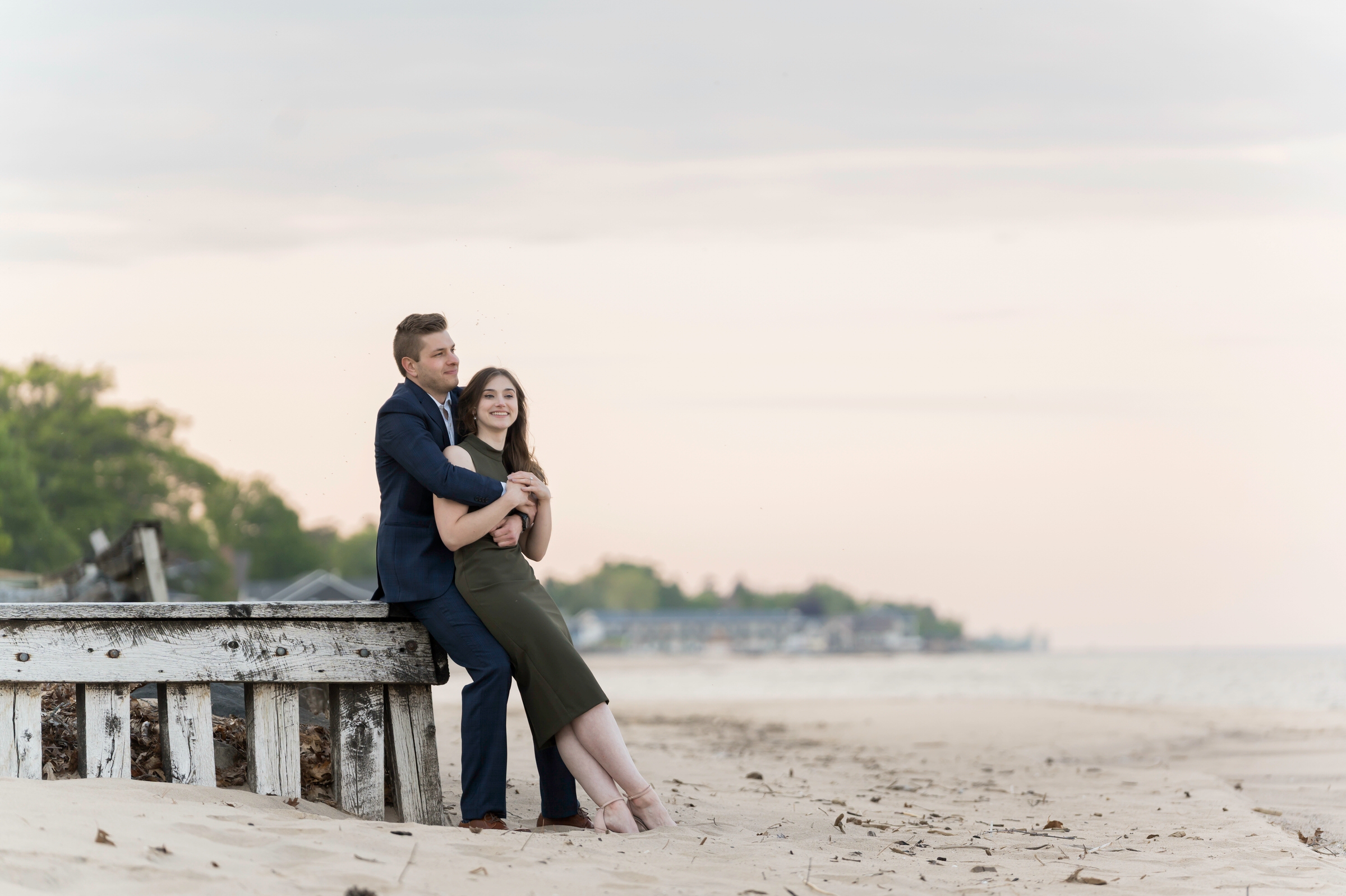 Couple sit embraced on the corner of the pier on the shores of Oscoda